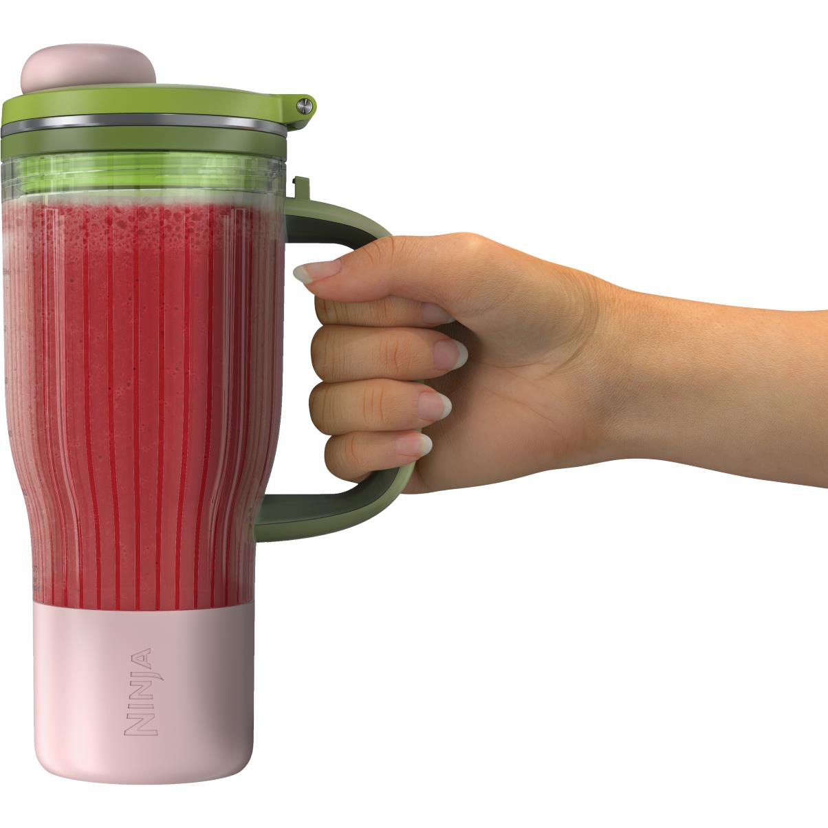 Blender jar with red smoothie, pink bottom, and green handle held by hand