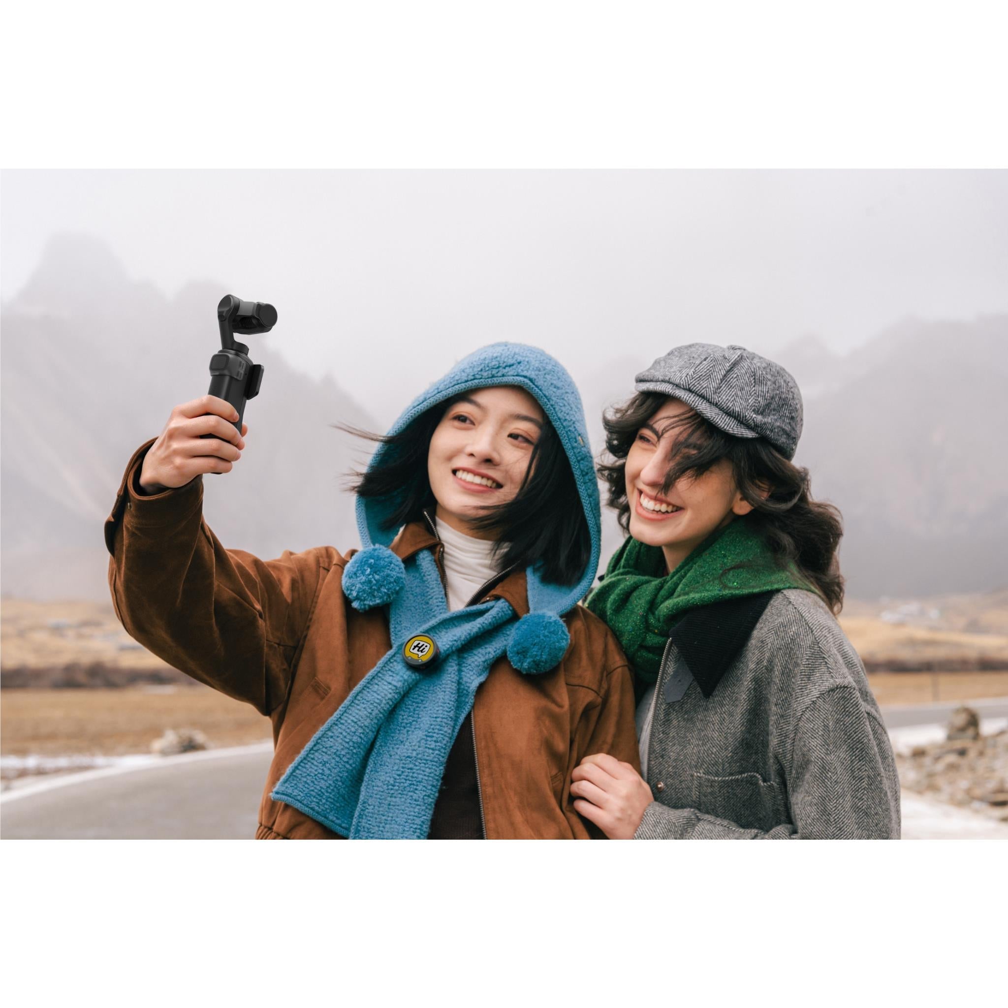 Black gimbal camera held outdoors, showing a live preview on the screen