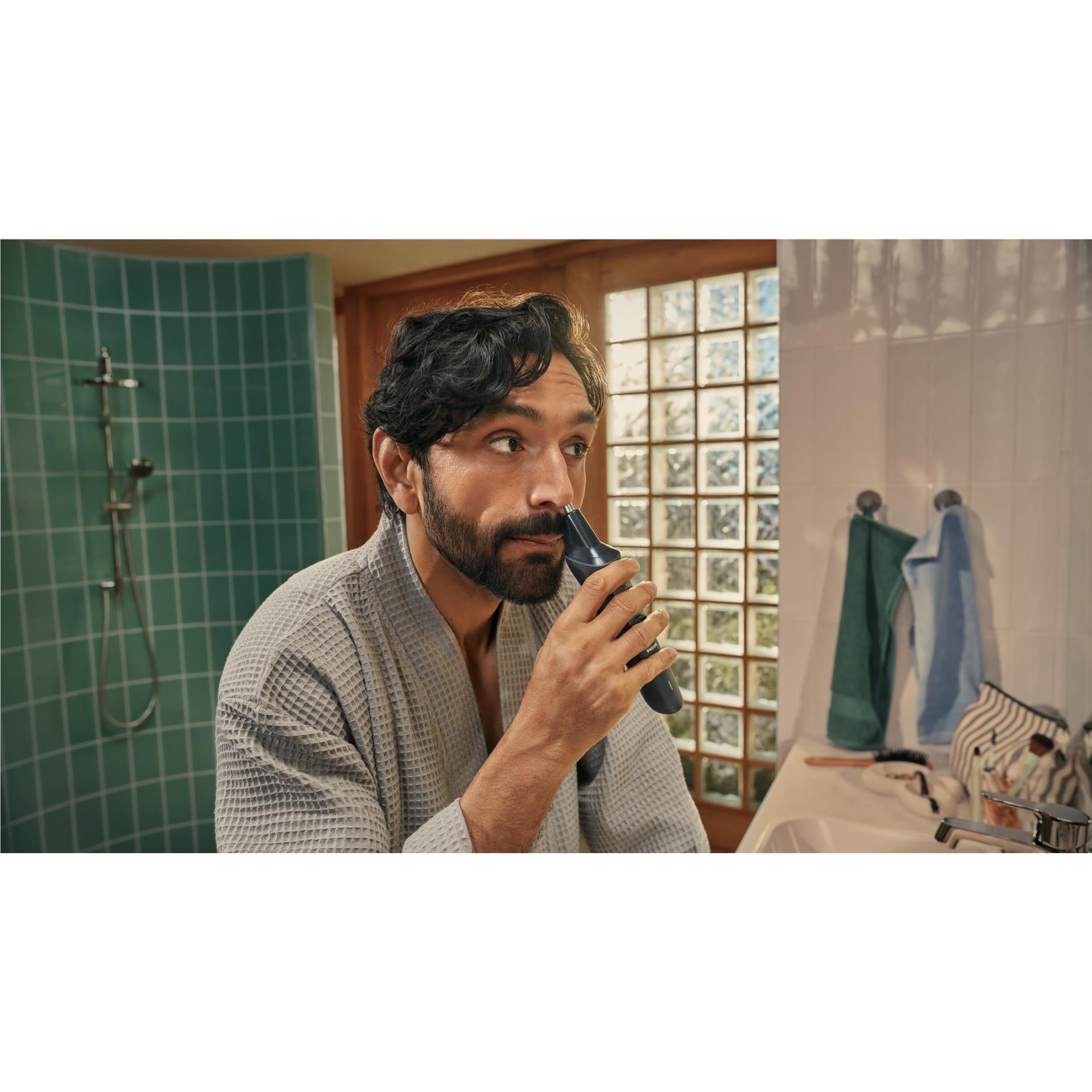 Handheld black trimmer used on a man's beard near the chin and jawline
