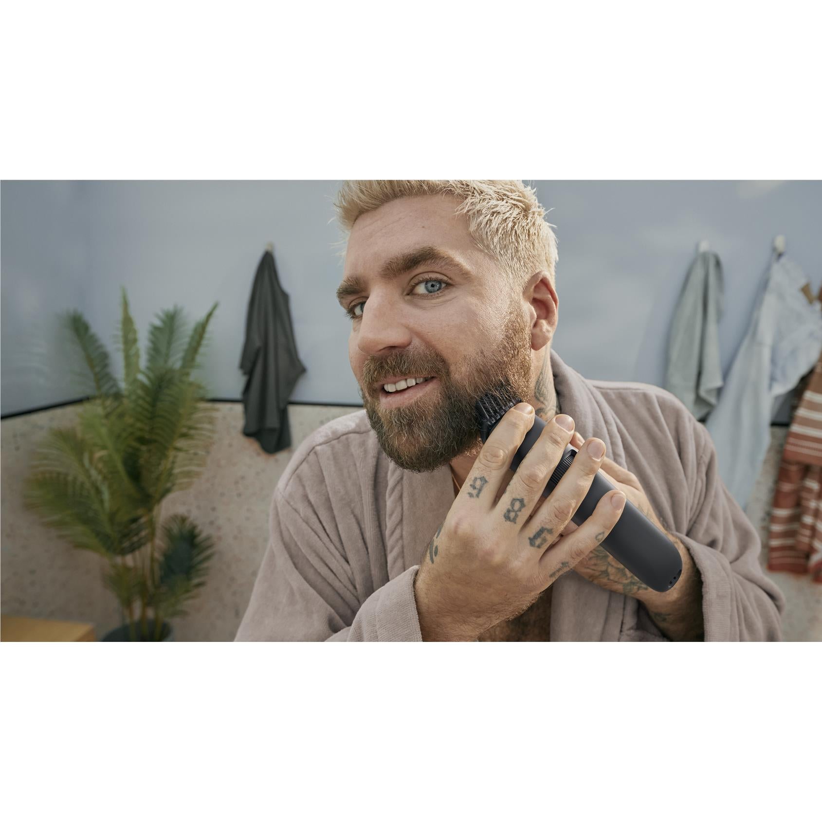 Beard trimming: man using a Philips beard trimmer while grooming