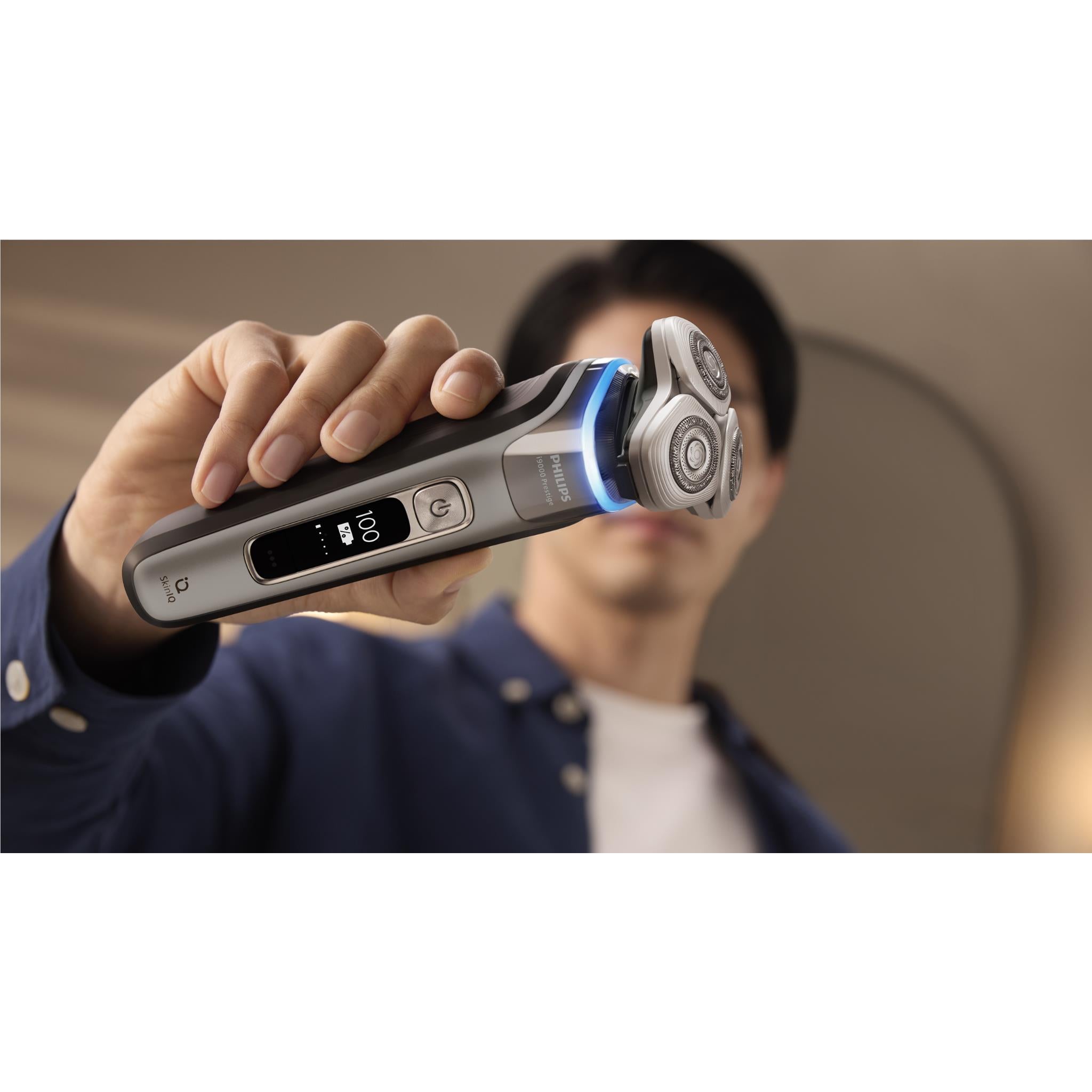 Electric shaver held to face with blue light on