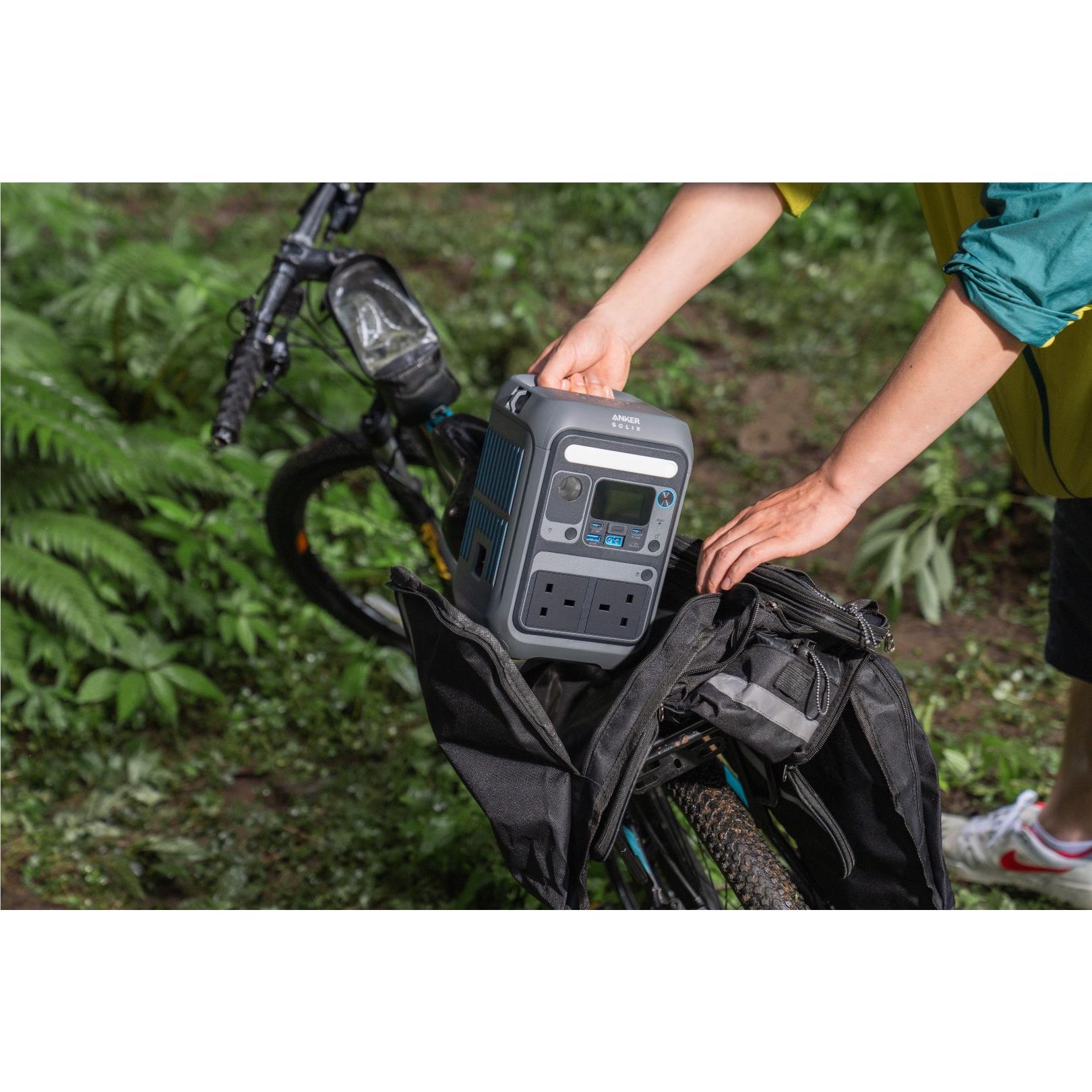 Grey Anker SOLIX portable power station on outdoor gear with illuminated outlets
