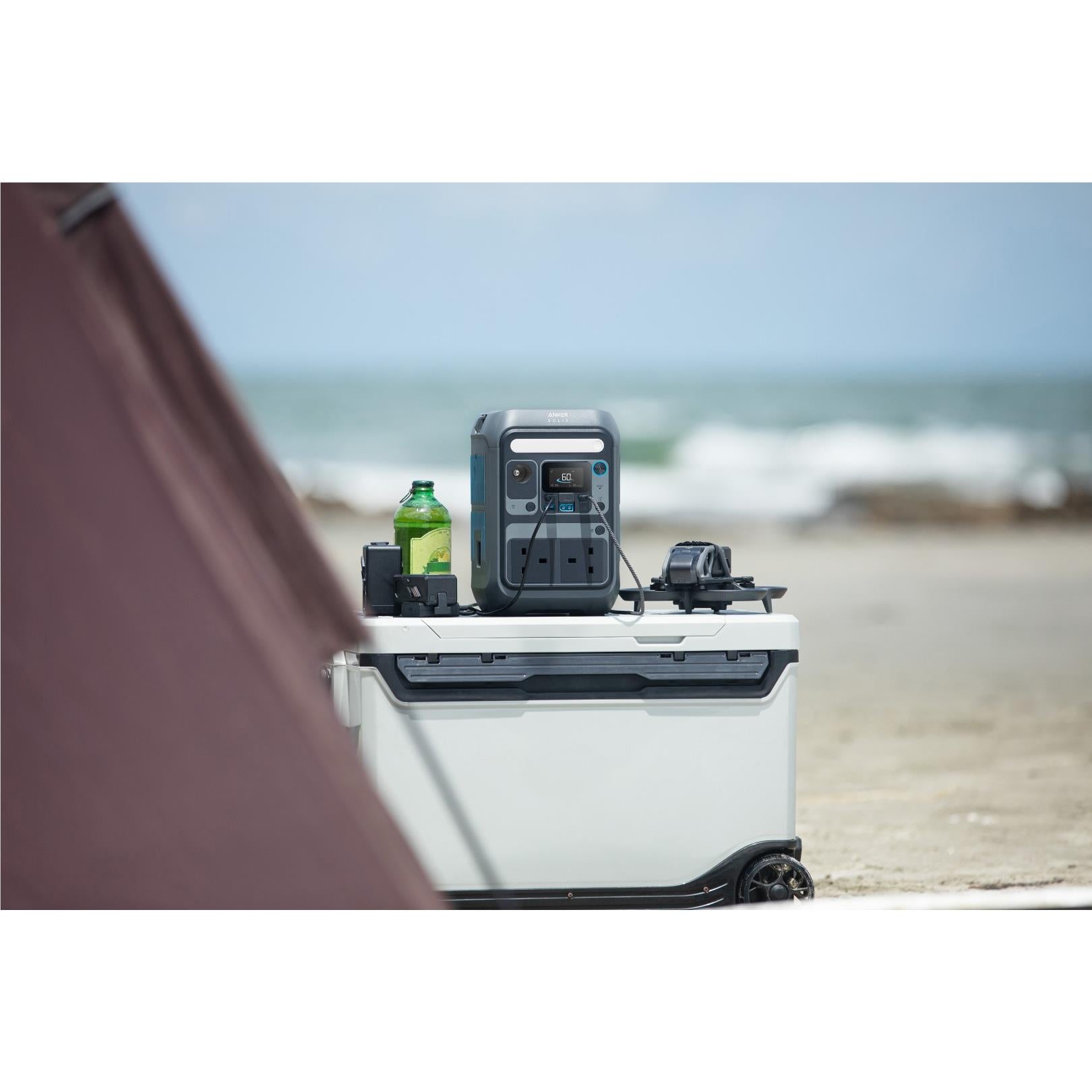 Grey Anker SOLIX power station on a cooler near the beach with illuminated panel