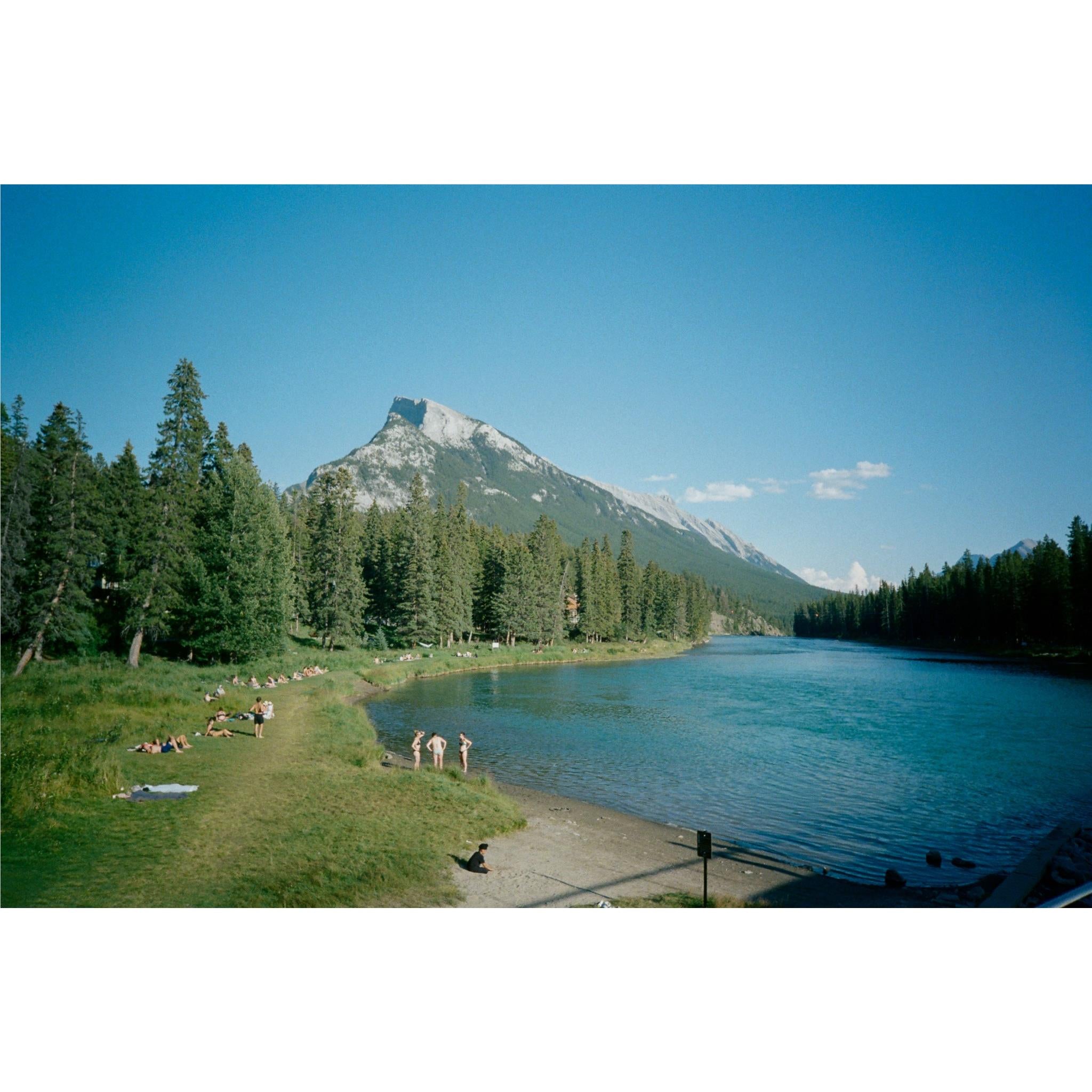 35mm film camera usage scene: lakeside path with trees and mountain in view
