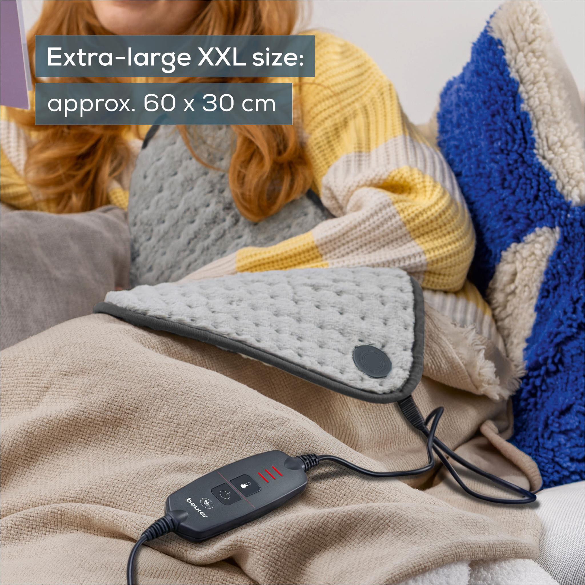 Grey XXL heating pad with controller and cord, shown on a couch