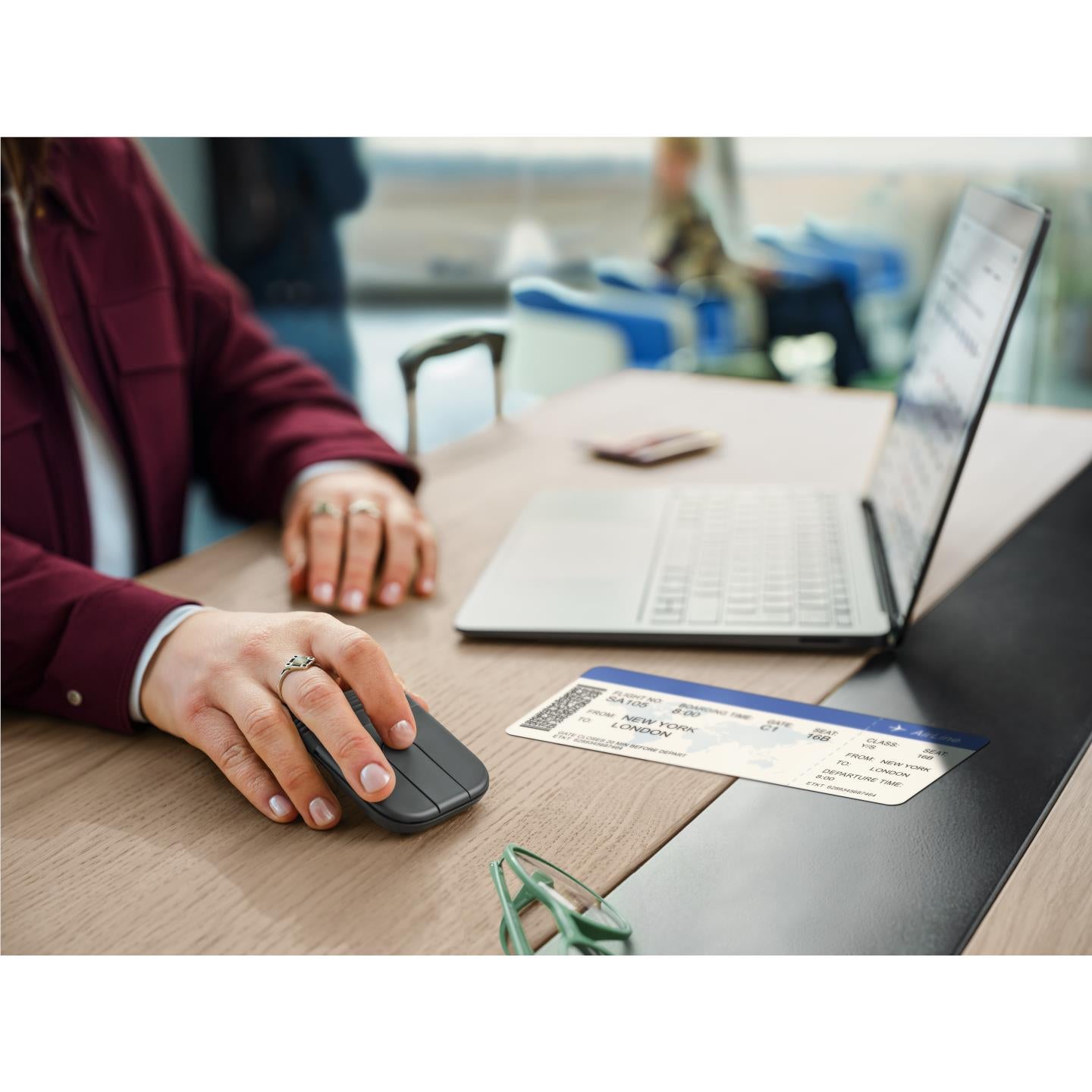 Person using foldable wireless mouse on office desk beside a laptop
