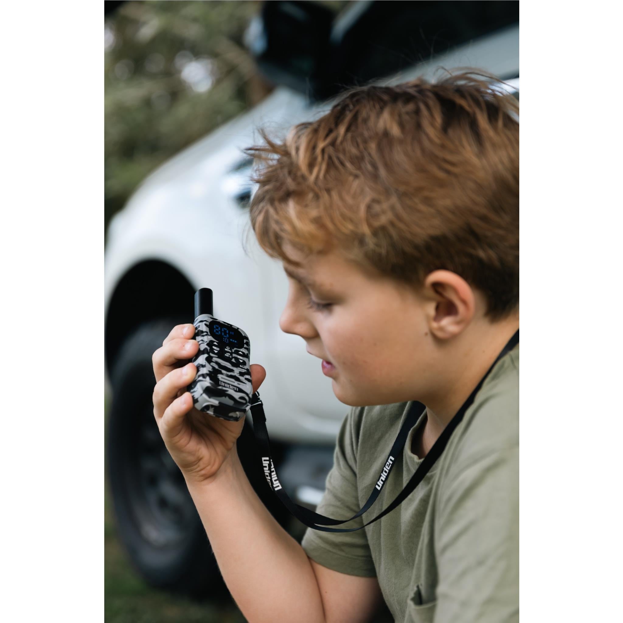 Camouflage UHF kid-zone radio held up near face, front display visible
