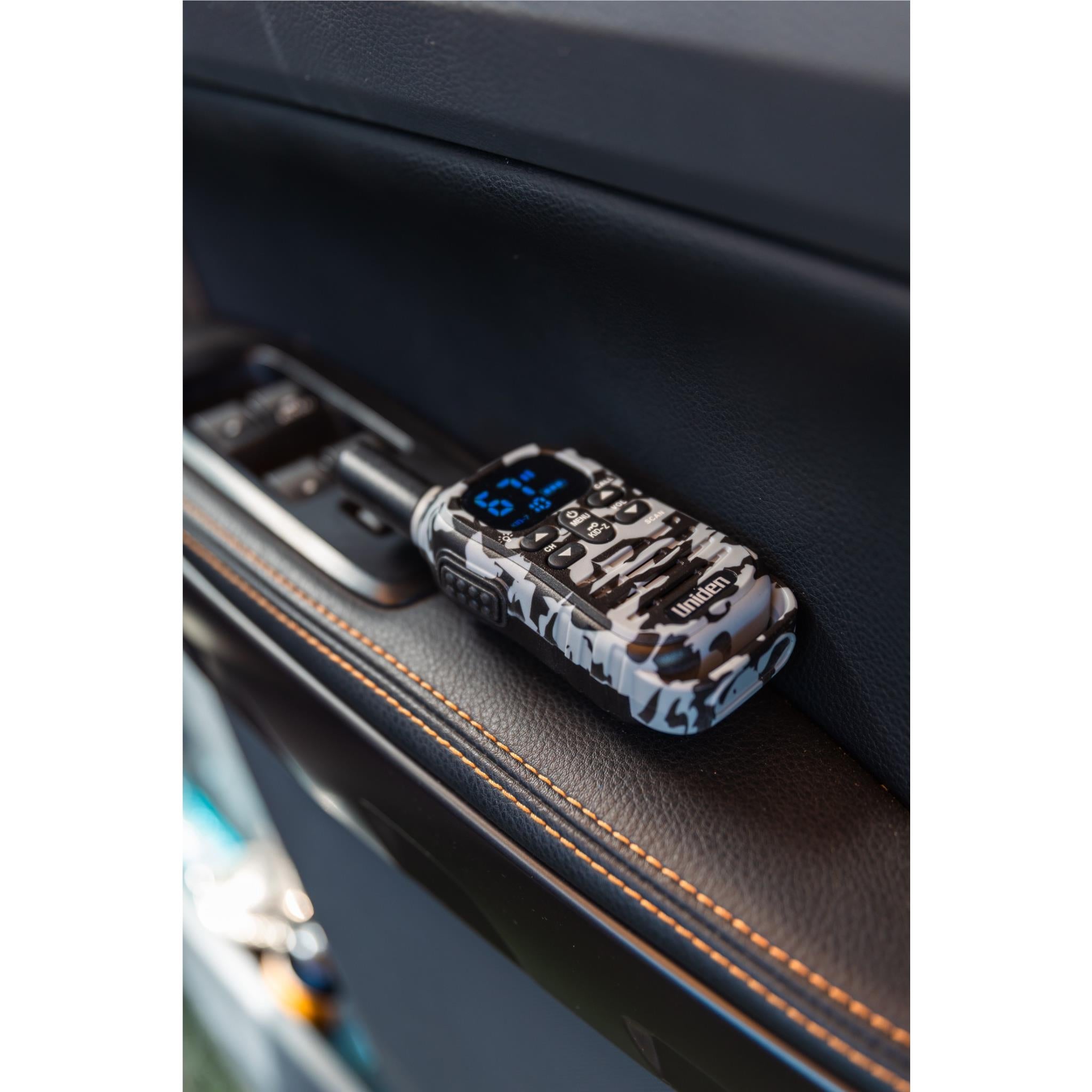 Camouflage UHF kid-zone radio resting on car seat, keypad and blue display