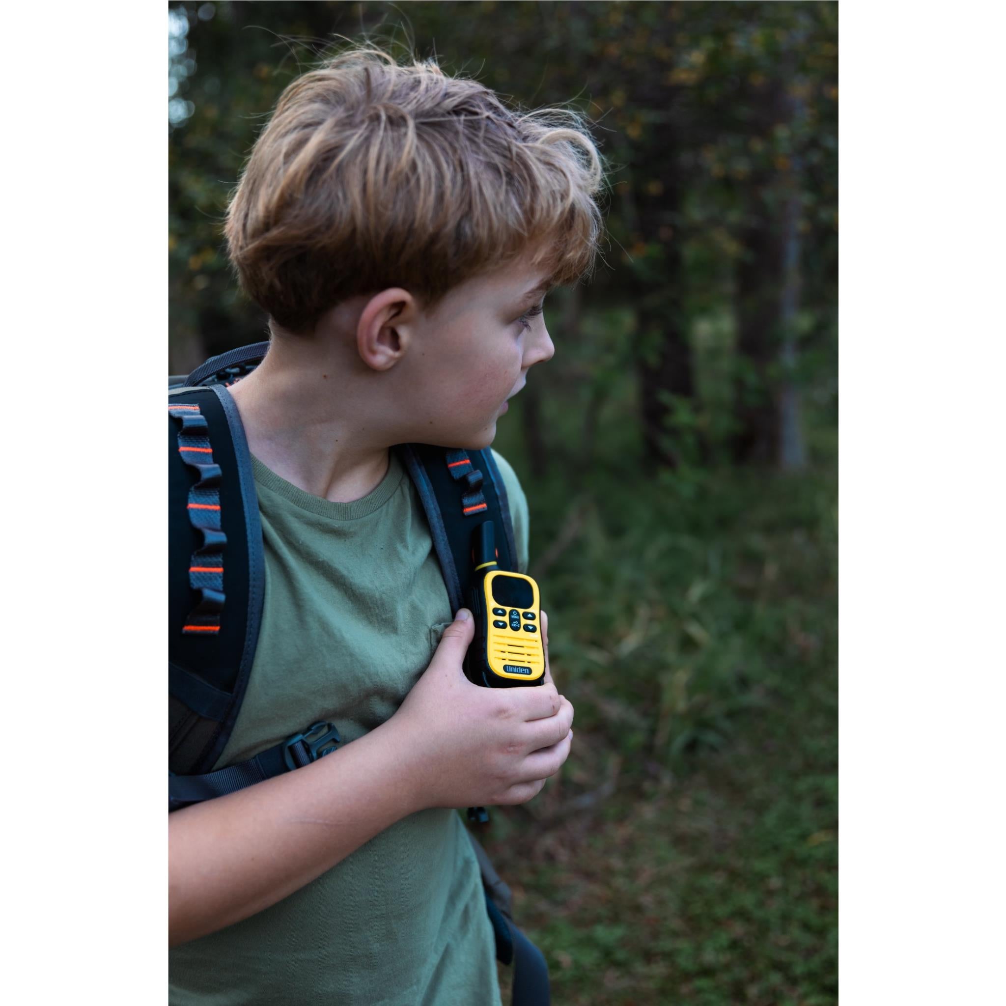Child holding a yellow Uniden UHF kid-zone radio with antenna and keypad