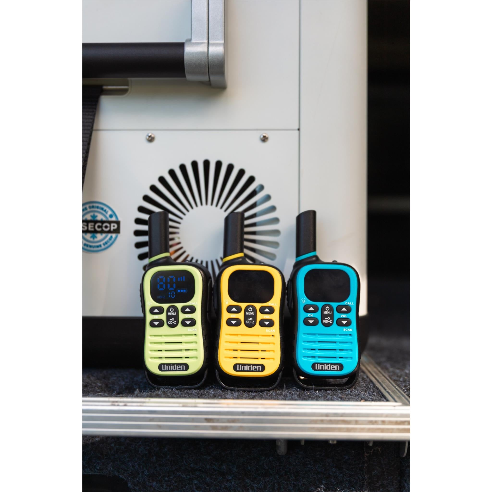 Three Uniden UHF kid-zone radios (green, yellow, blue) standing together