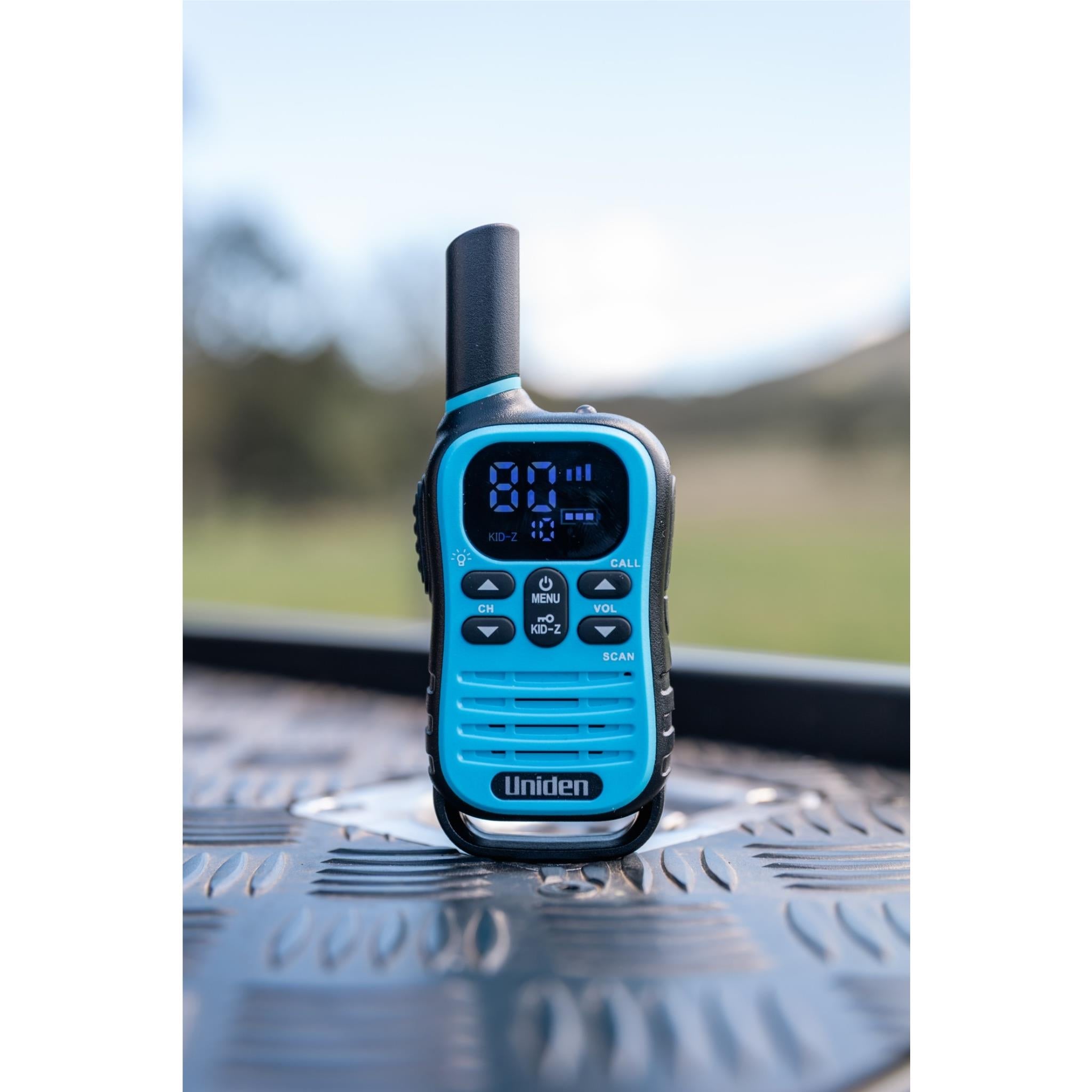 Blue Uniden UHF kid-zone radio standing on textured metal surface