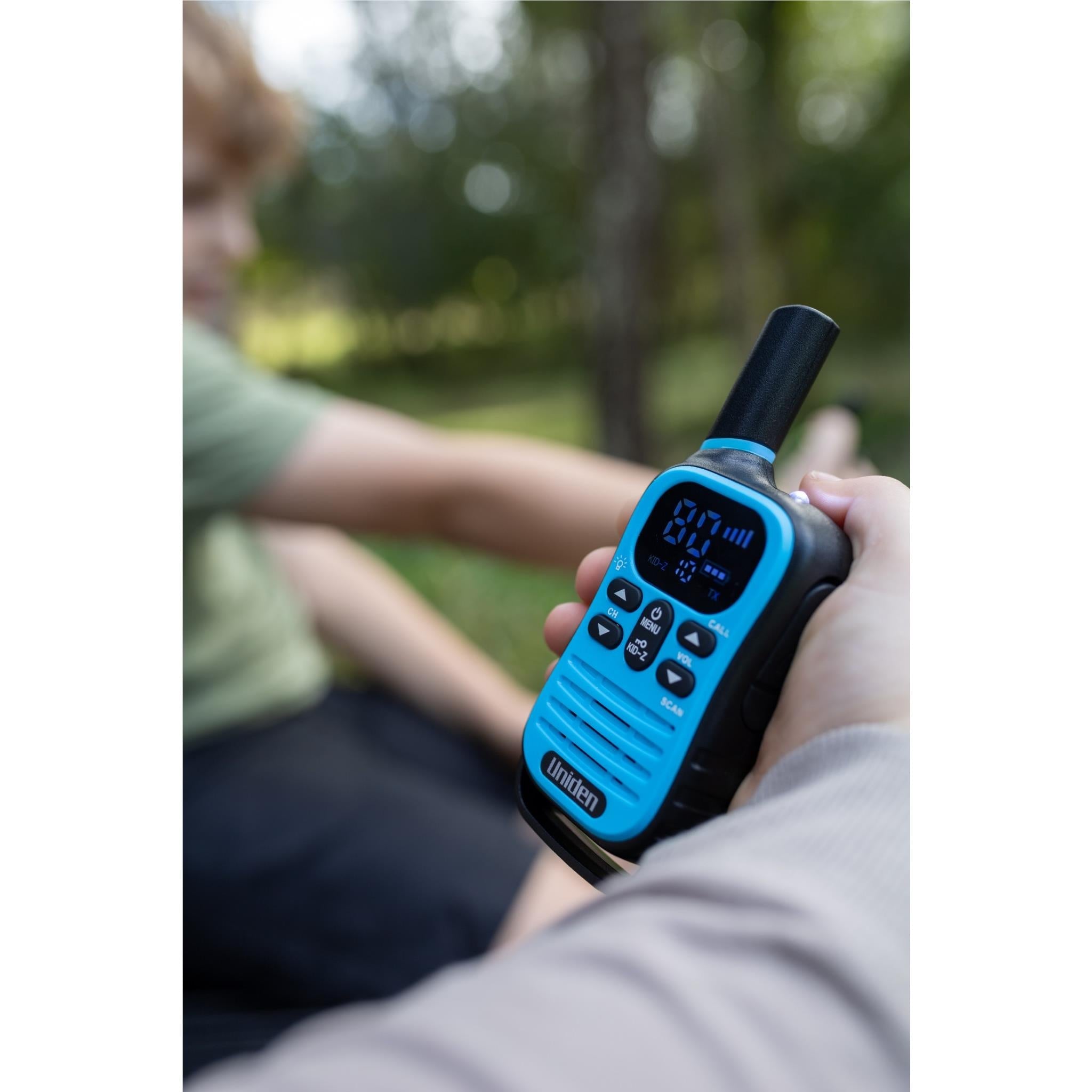 Uniden Kid-Zone Plus UHF radio, blue, held in hand with lit display