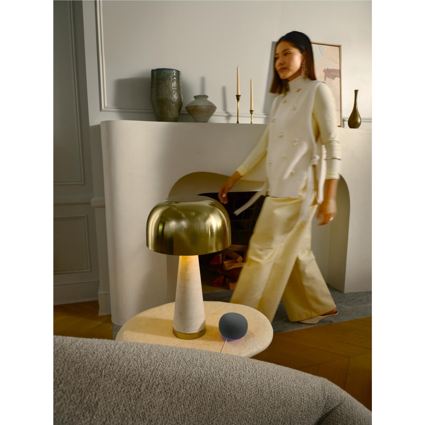 Smart speaker with textured dome and purple LED ring on floor beside a lamp