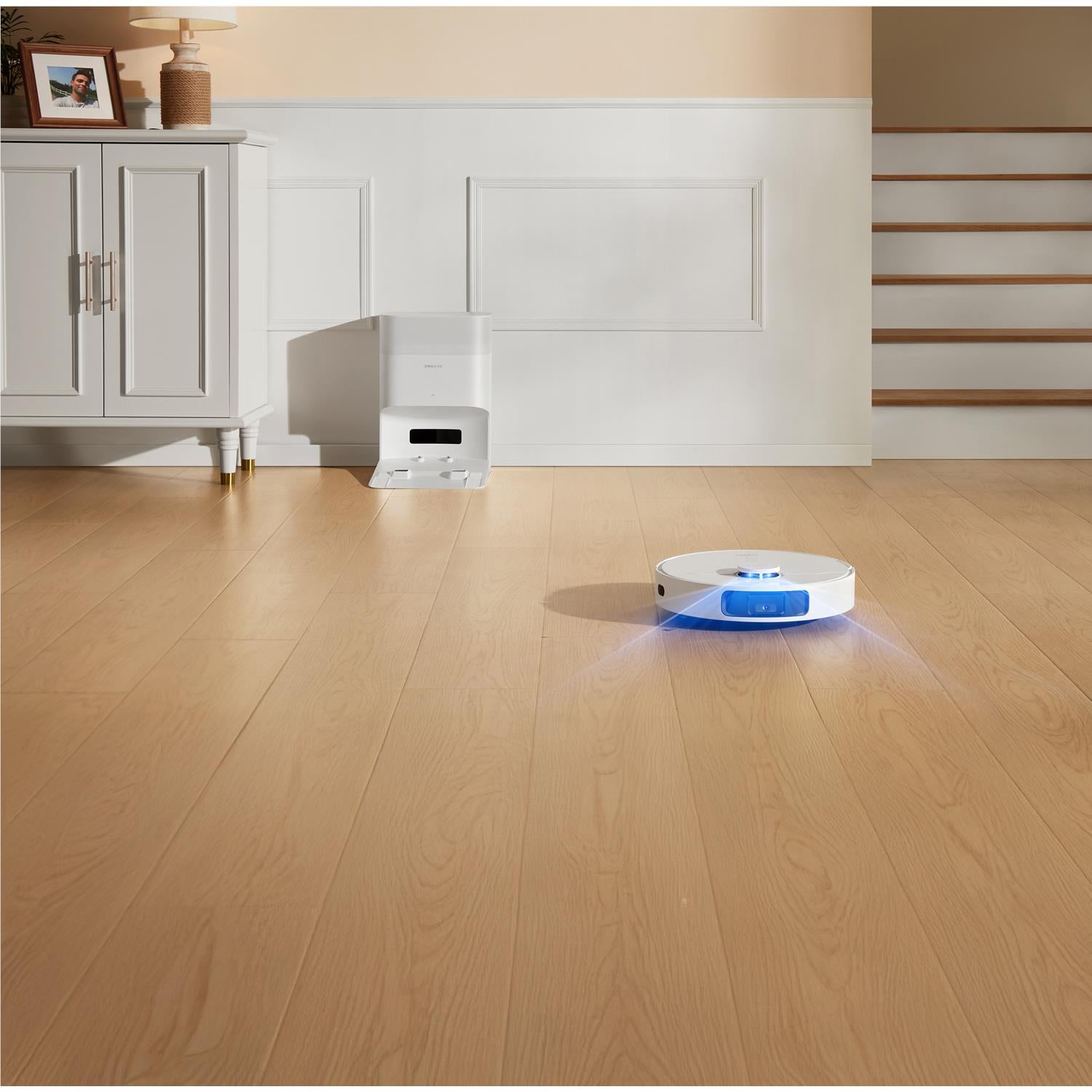 Dreame robot vacuum and mop on hardwood floor with blue indicator light