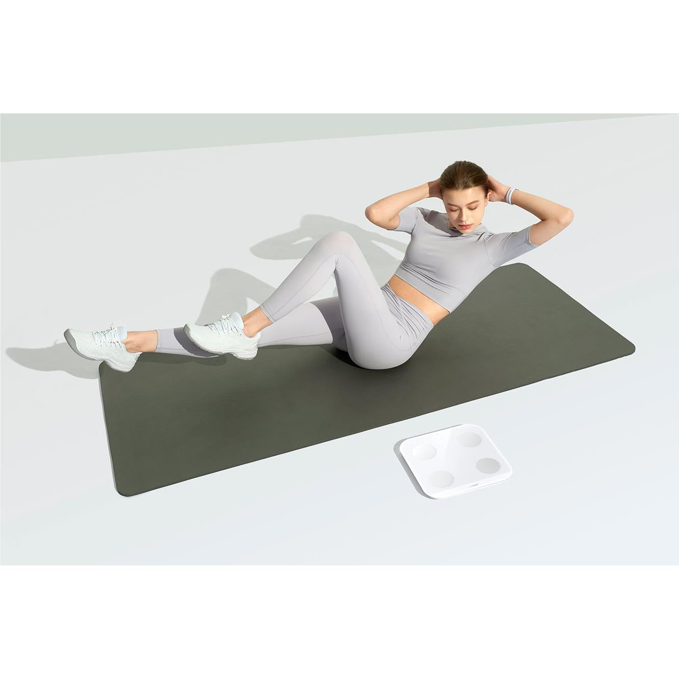 Frosty white body fat scale on the floor under a person lying on a mat