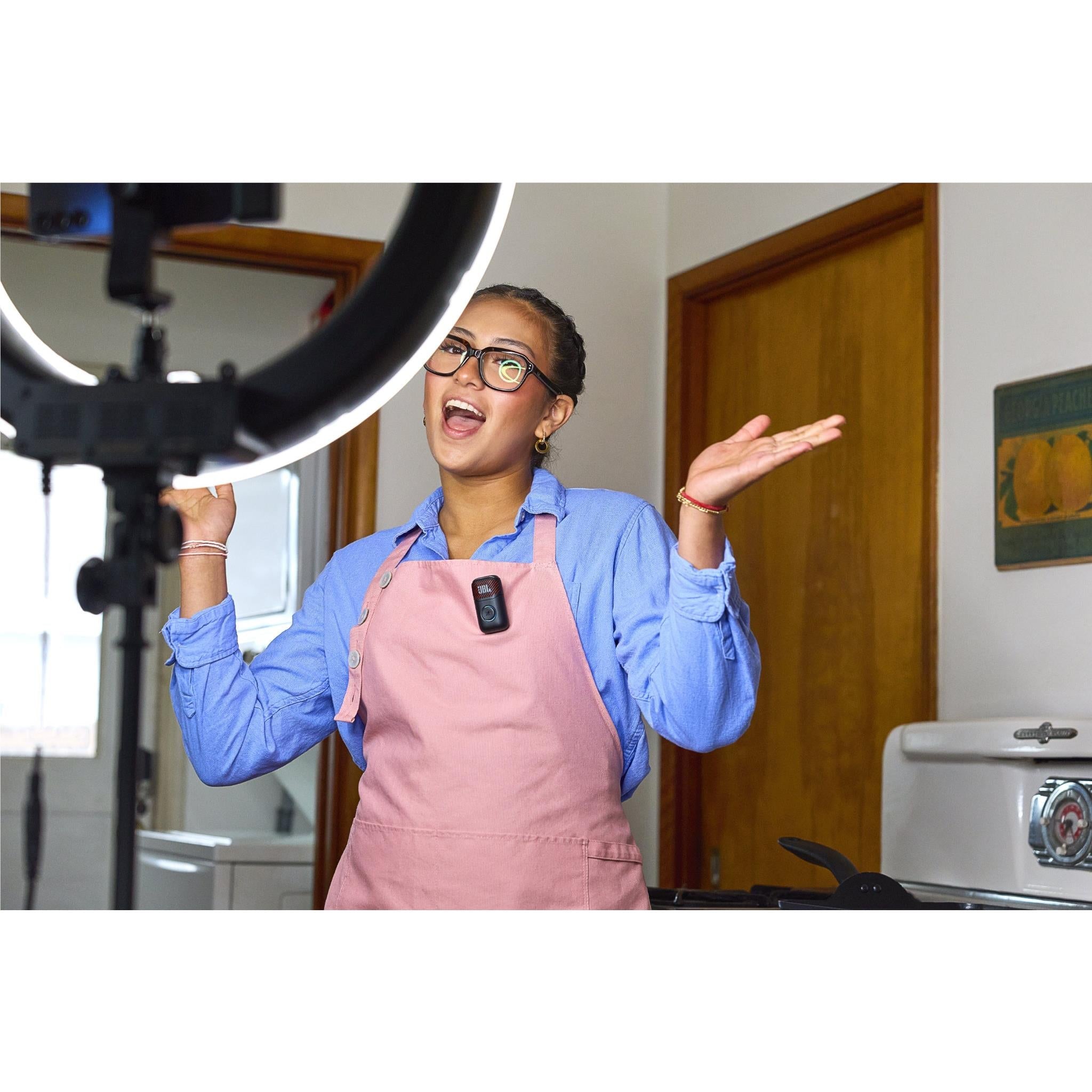 Person singing into a mini wireless karaoke microphone while wearing a pink apron