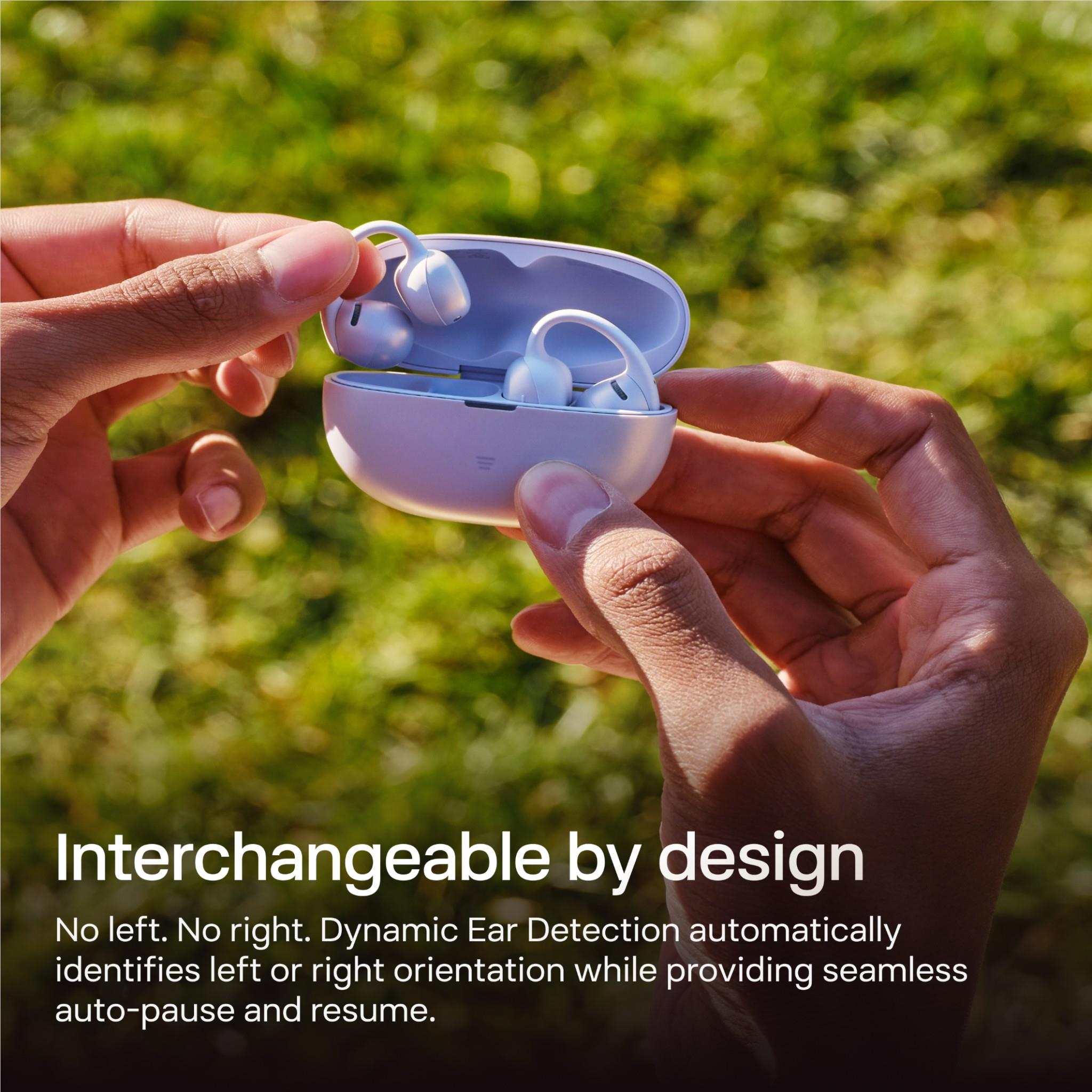 Hands holding lavender open-ear earbuds in a charging case with earbuds seated