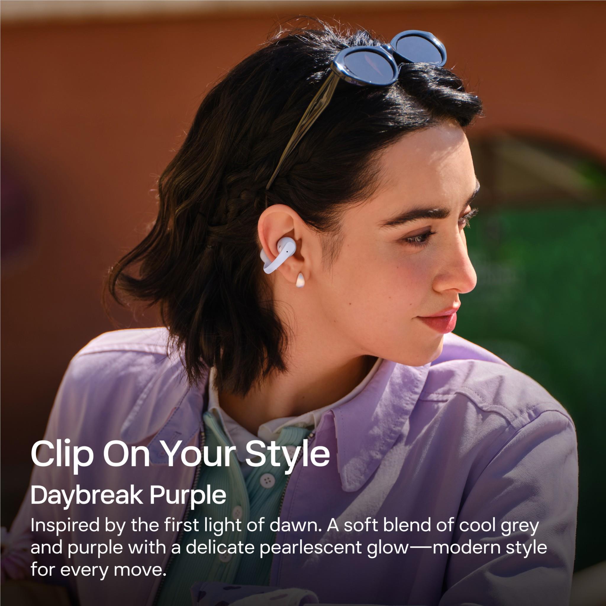 Open-ear wireless earbuds worn by a person, Daybreak Purple