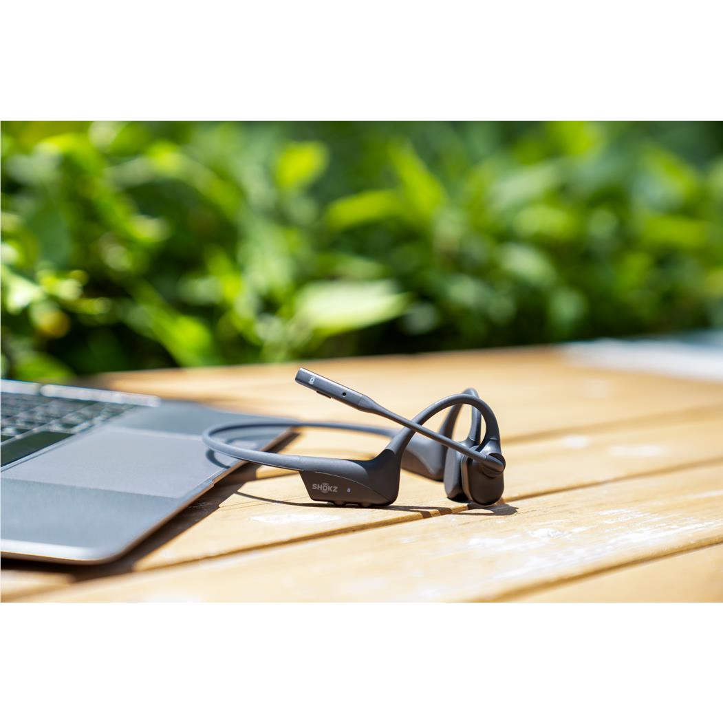 Black open-ear bone conduction headset on outdoor table with boom microphone