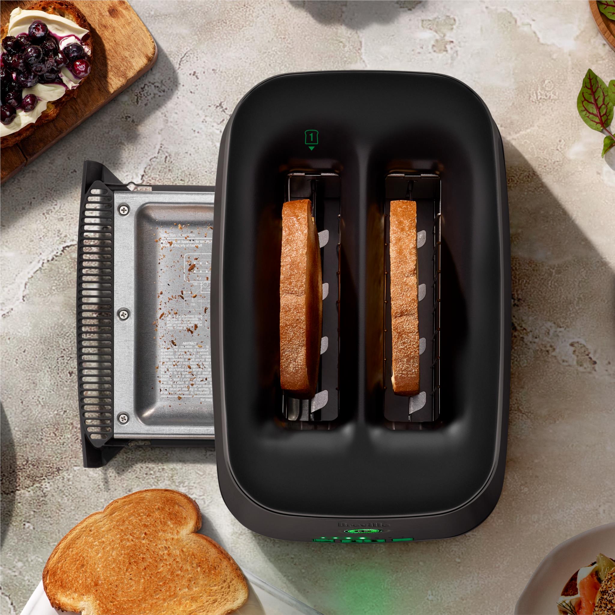 Black two-slice toaster with two bread slices in the heating slots