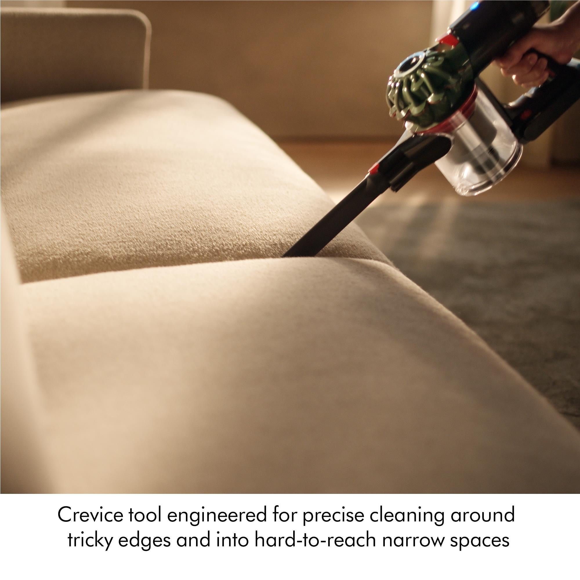 Dyson cordless vacuum cleaner cleaning sofa edge with crevice tool
