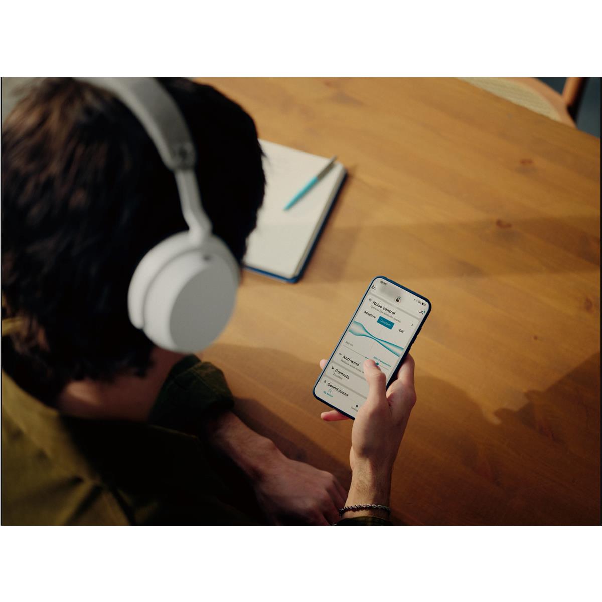 Over-ear headphones with white earcups as a person holds a smartphone