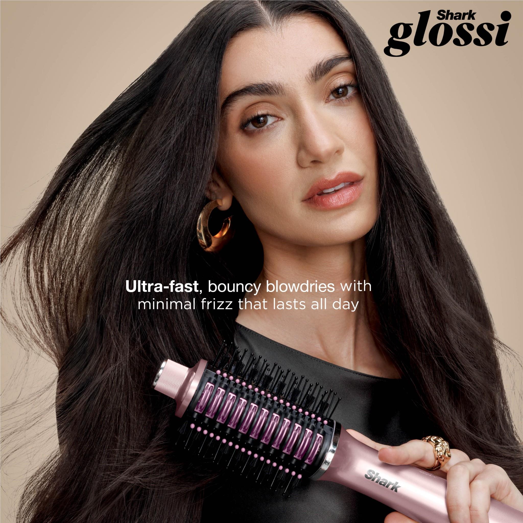 Pink hot air hair styler held near long black hair with round brush barrel