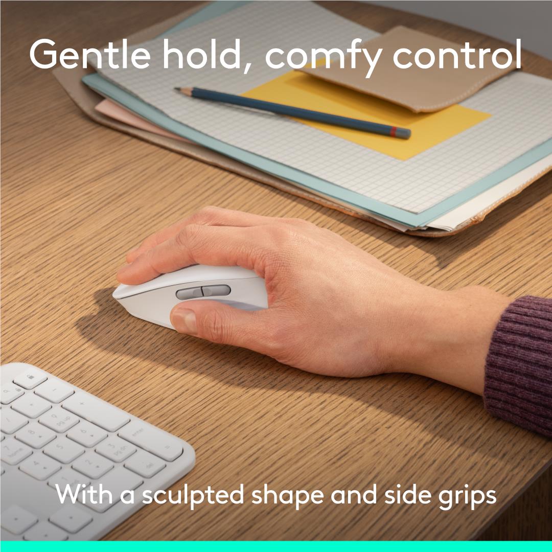 Off-white Logitech mouse in hand on a desk, with keyboard keys visible nearby