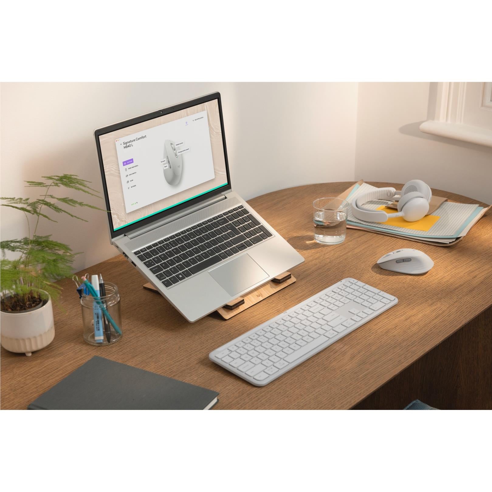 Off-white mouse on a work desk beside a laptop, keyboard, and notebook