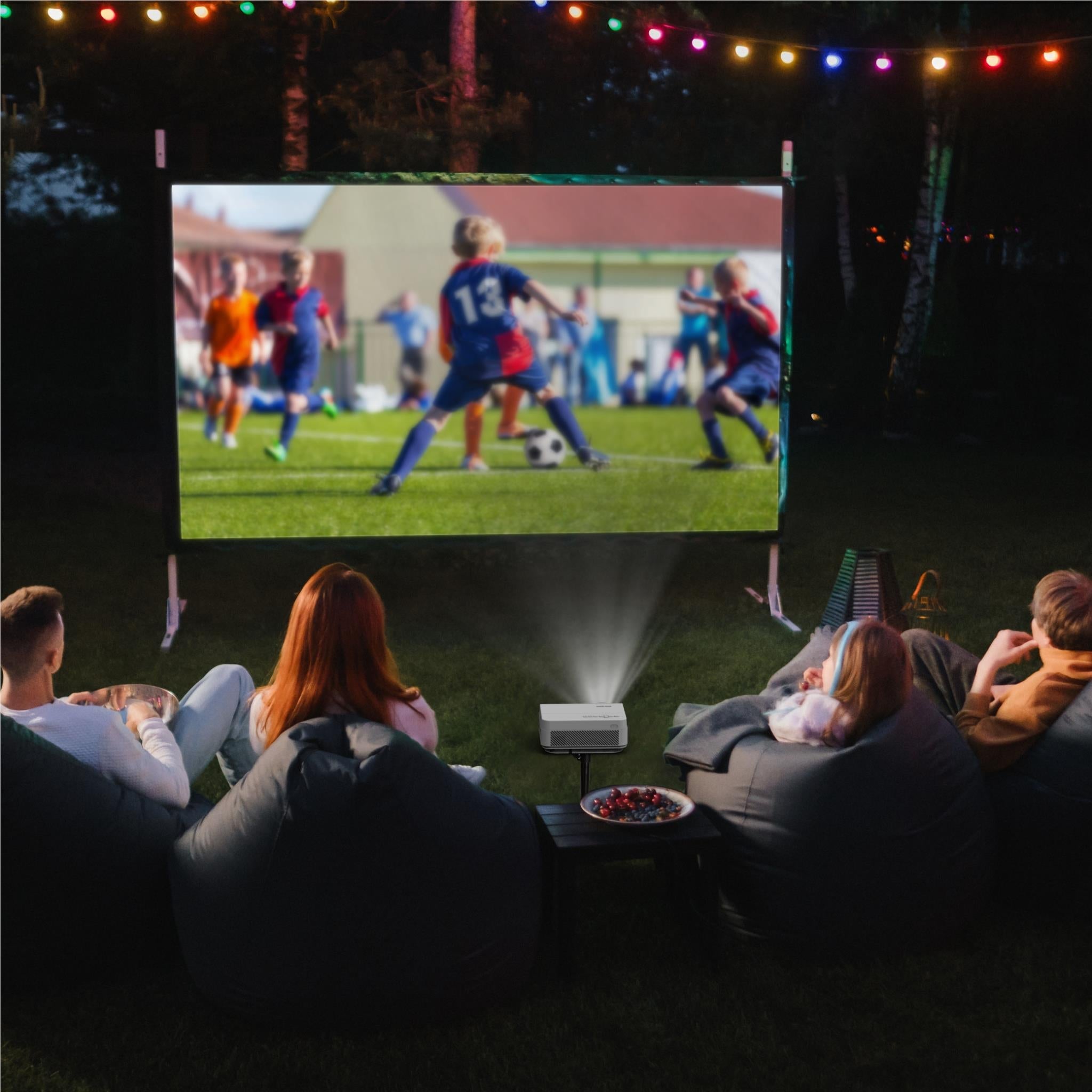 Inflatable outdoor screen with white projector and seated group viewing on backyard patio