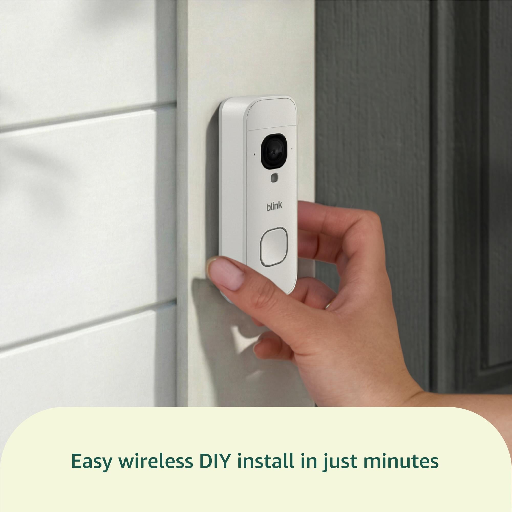 White video doorbell being installed on a doorway wall by a hand