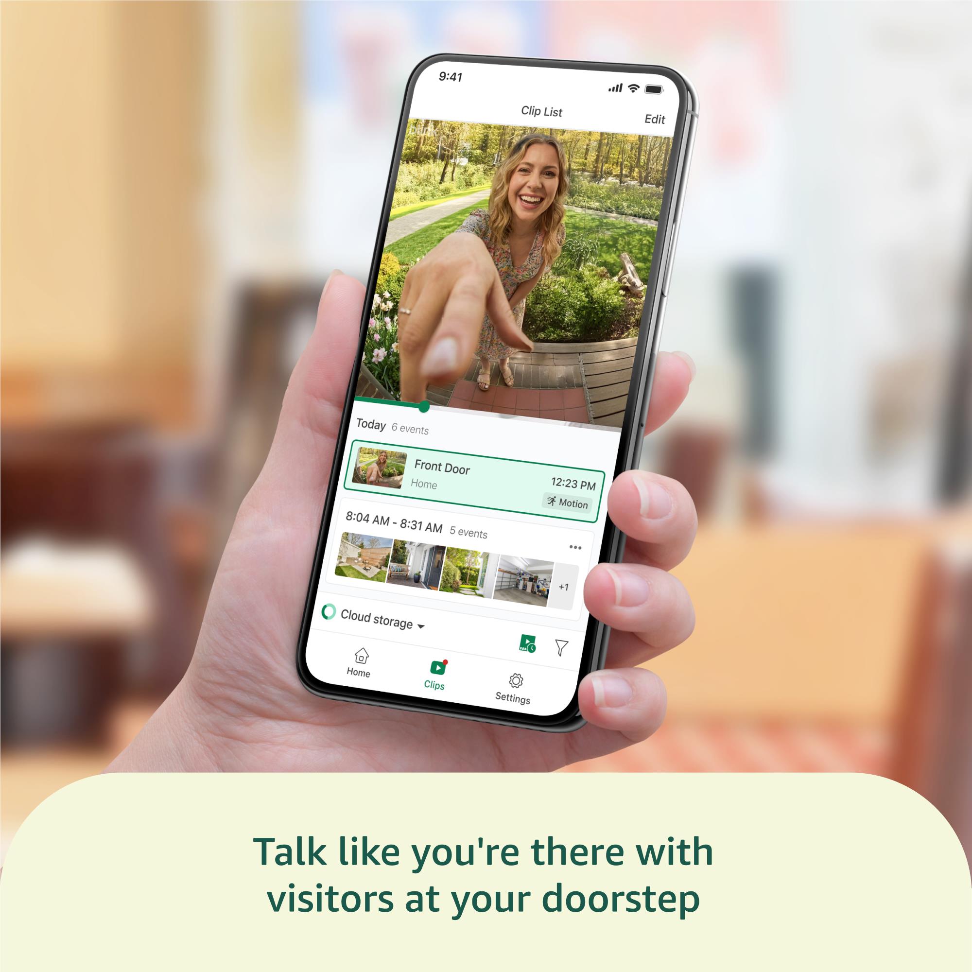 Hand holding a smartphone displaying front-door video from a white doorbell