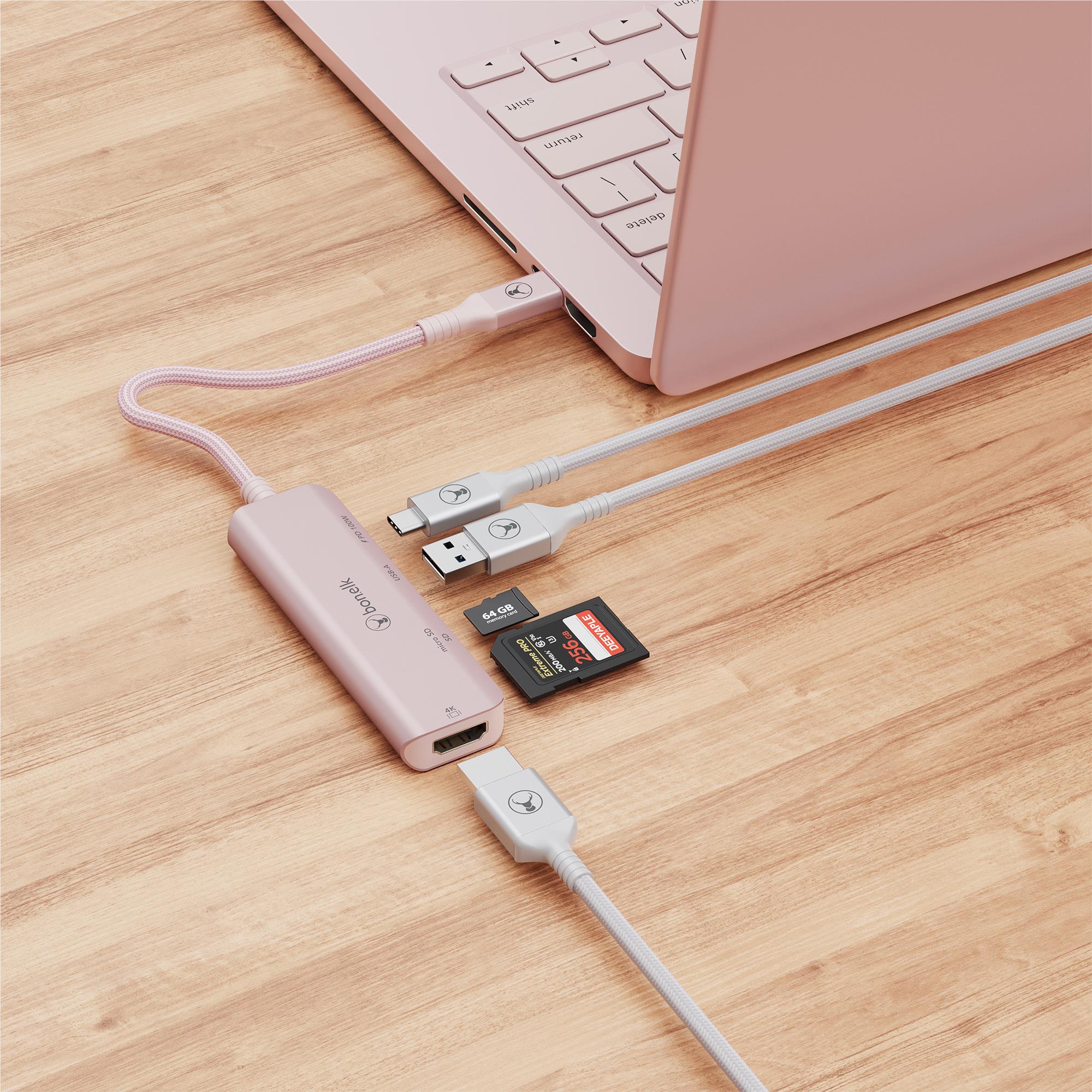 Blush pink USB-C hub connected to laptop with SD card and USB devices