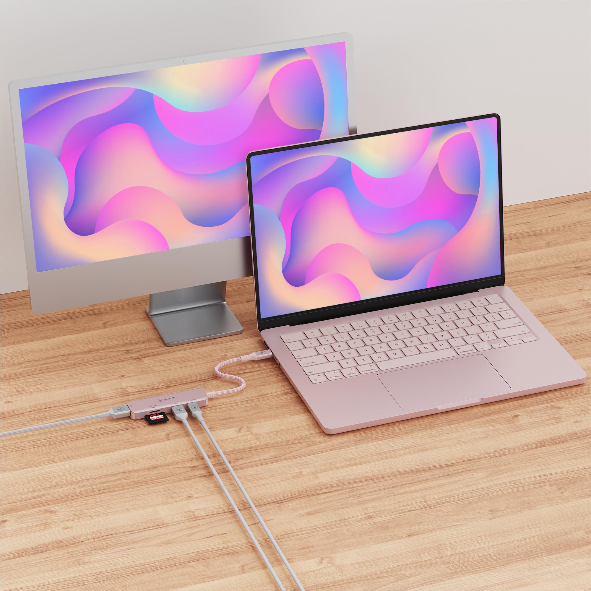 Blush pink USB-C hub connected to laptop powering two external displays