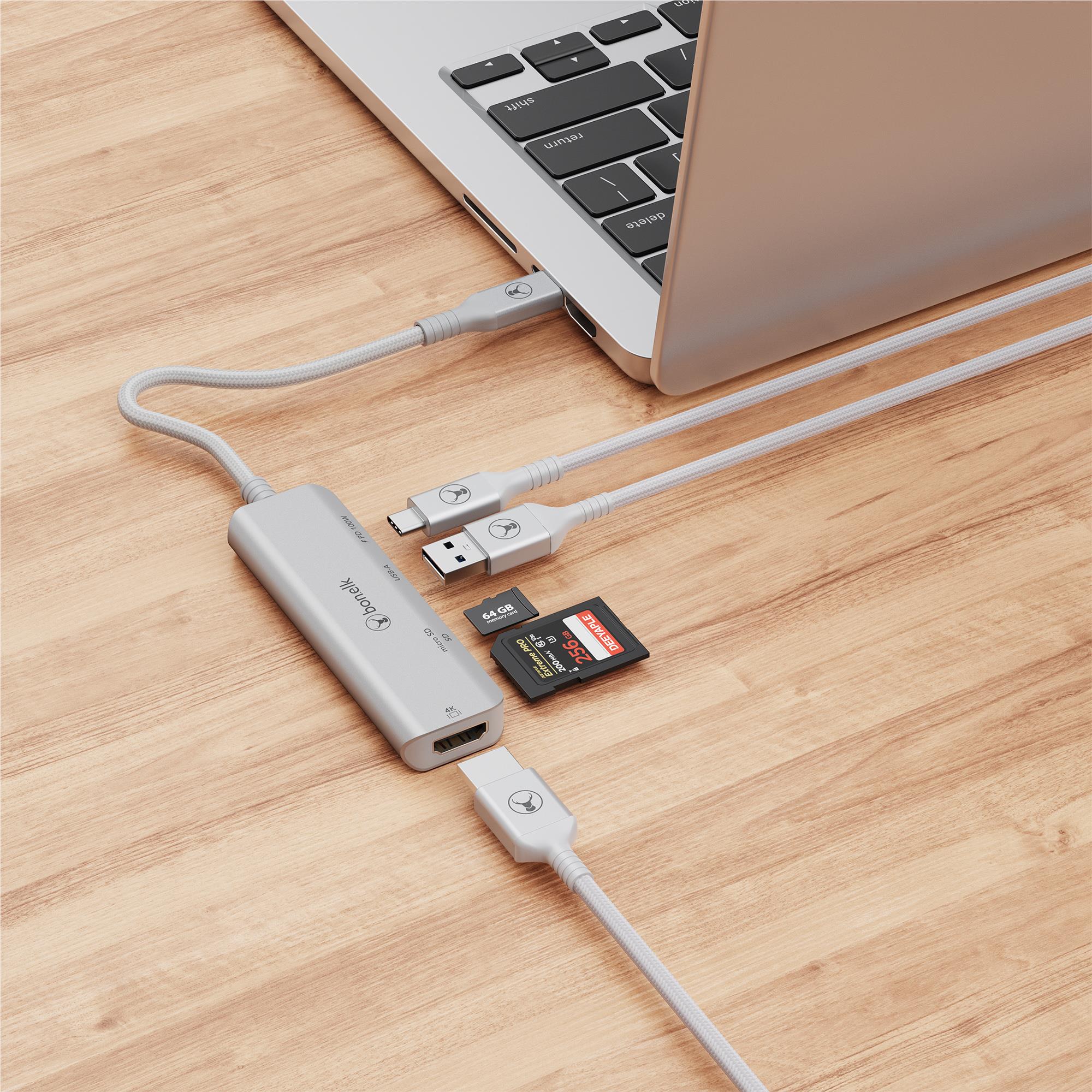 Silver grey USB-C hub with USB-A and SD card connected near laptop ports