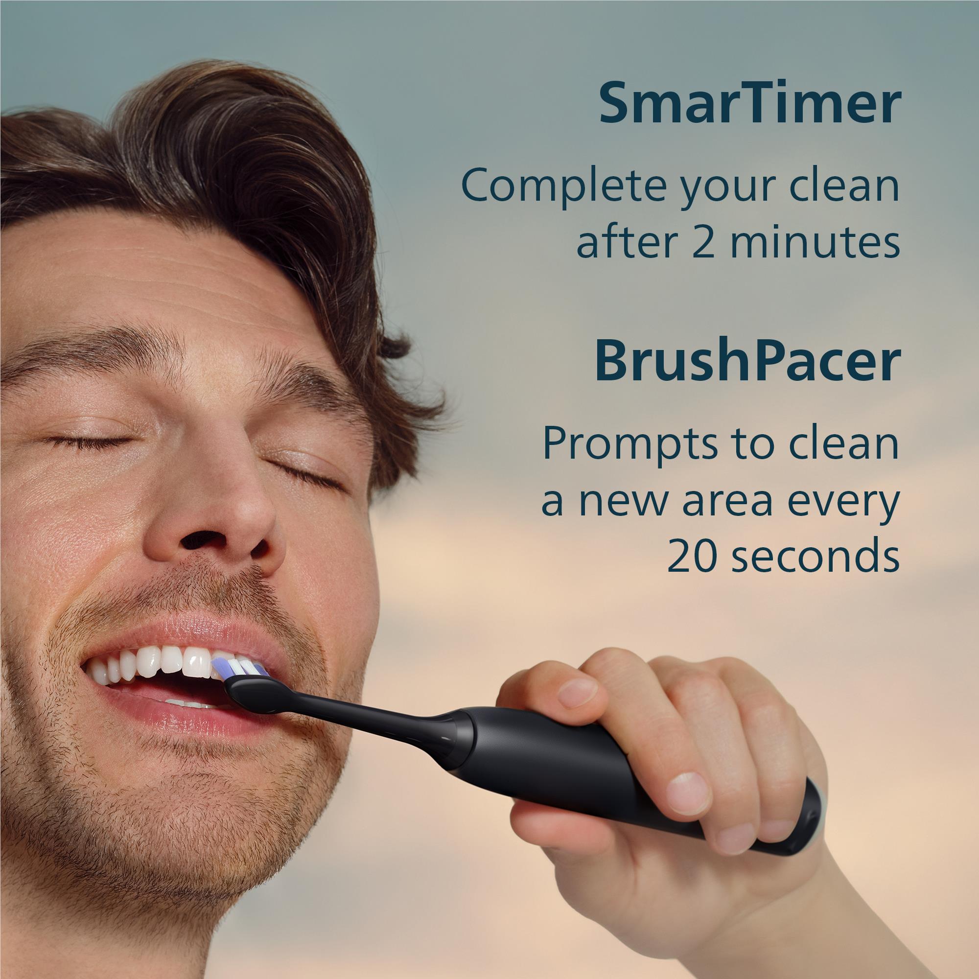 Black electric toothbrush in use, held near mouth with blue bristles