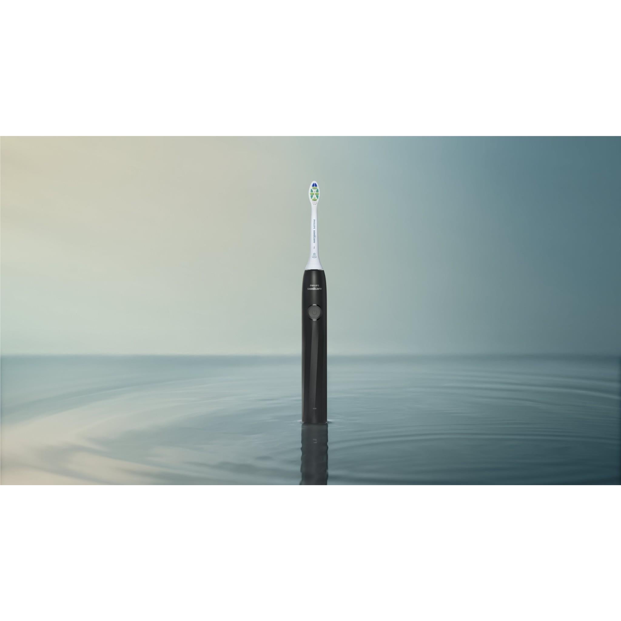 Black rechargeable electric toothbrush standing upright with white brush head