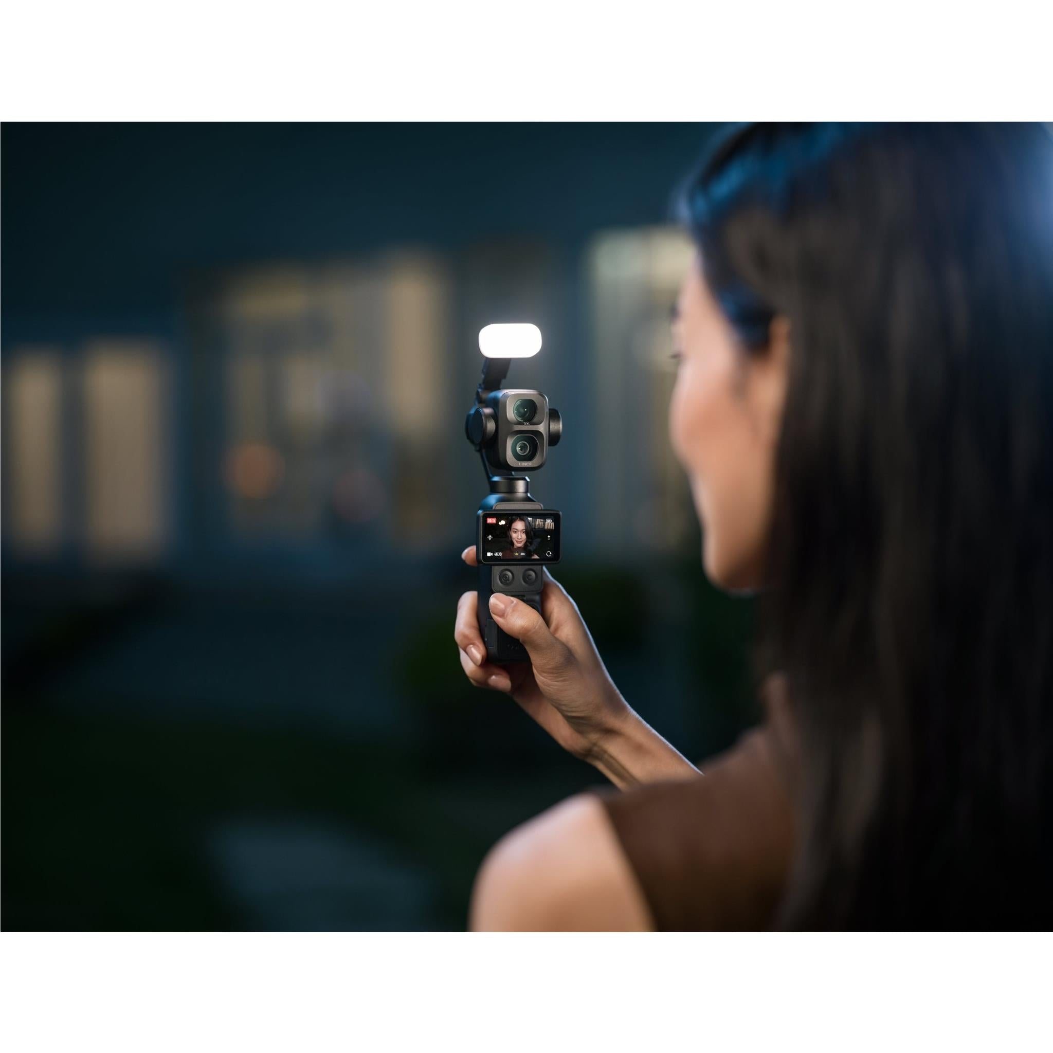 Black gimbal camera on mini tripod stand held up for filming with screen lit