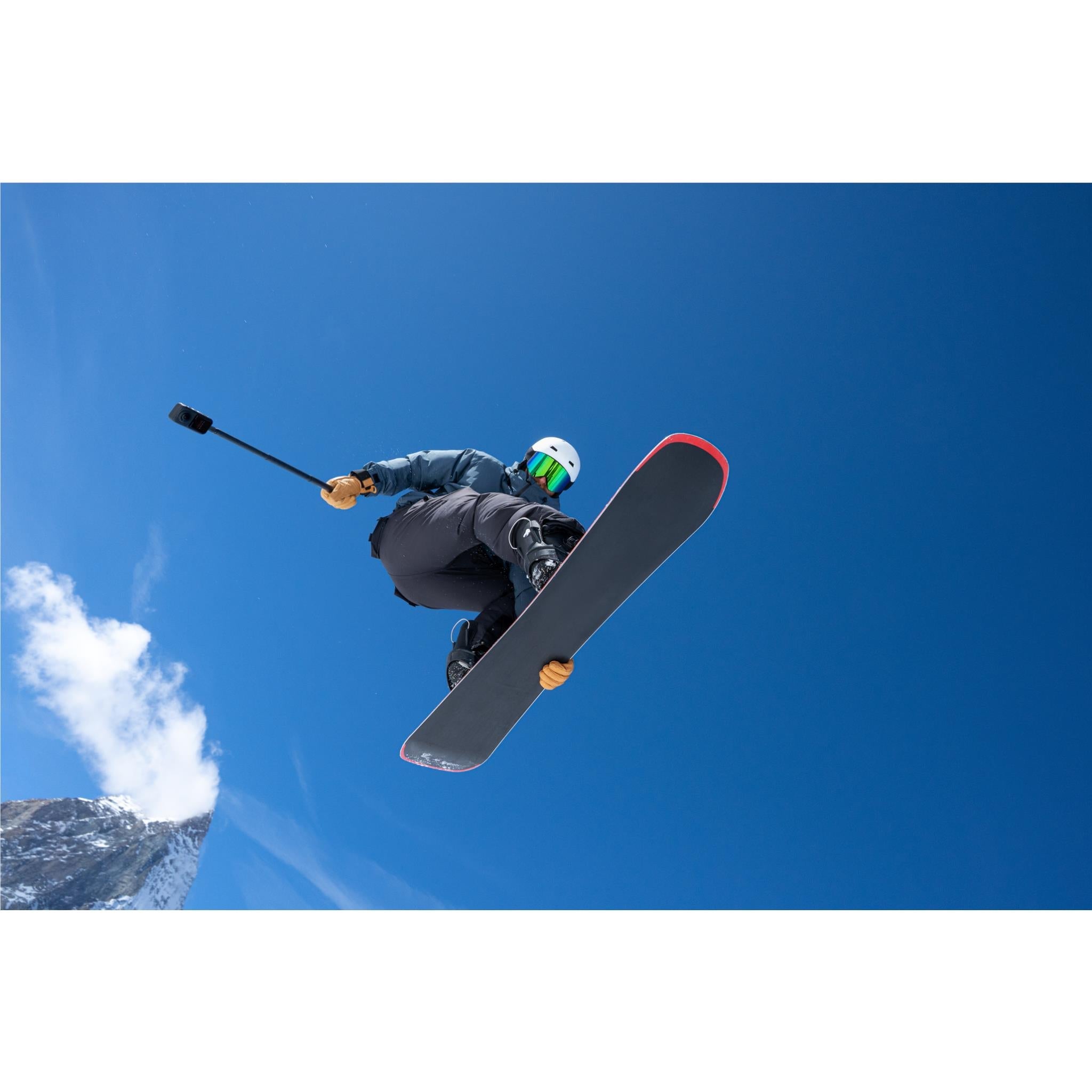 Black 360 action camera on selfie stick, angled view toward sky
