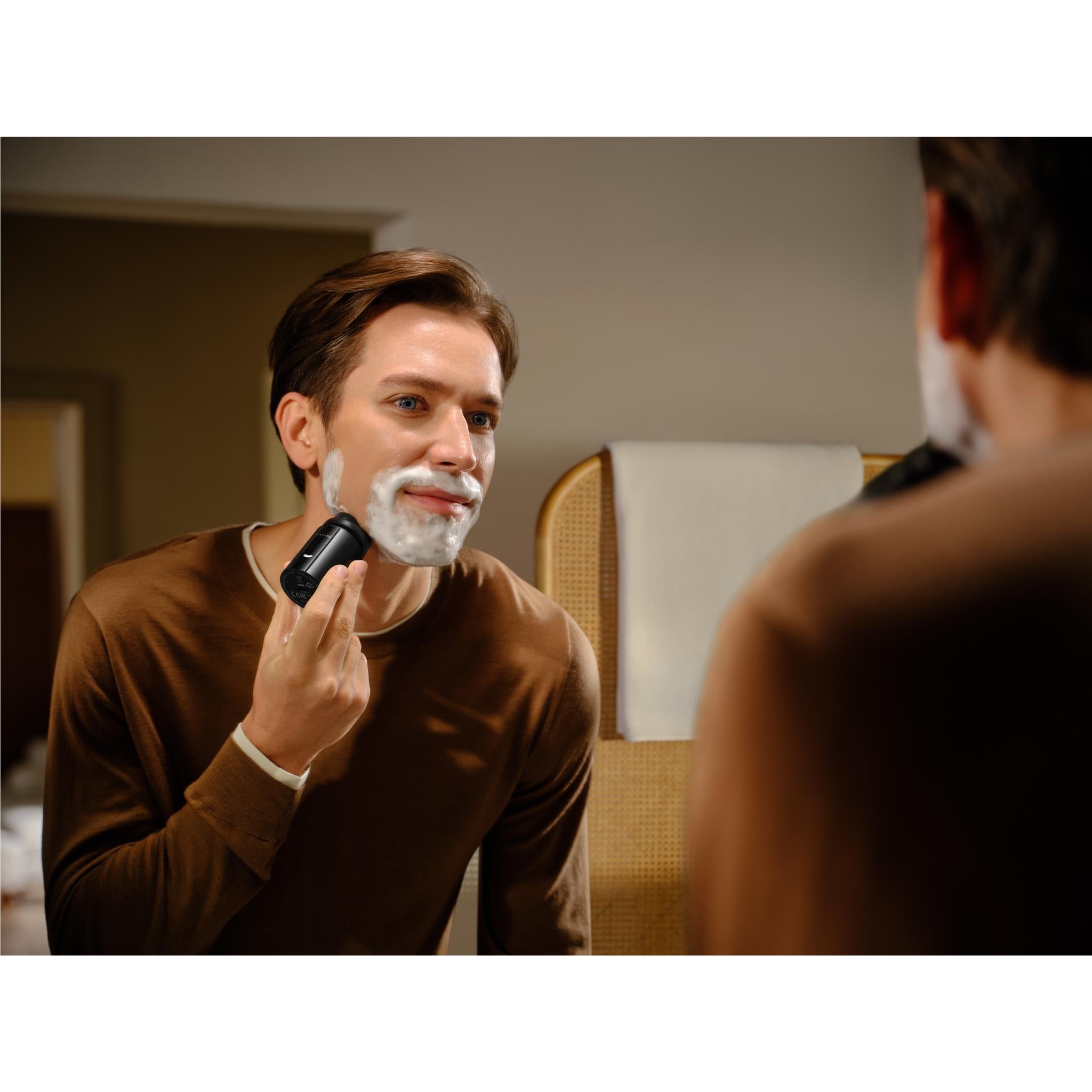 Electric beard shaver held to the face during shaving, with stubble visible