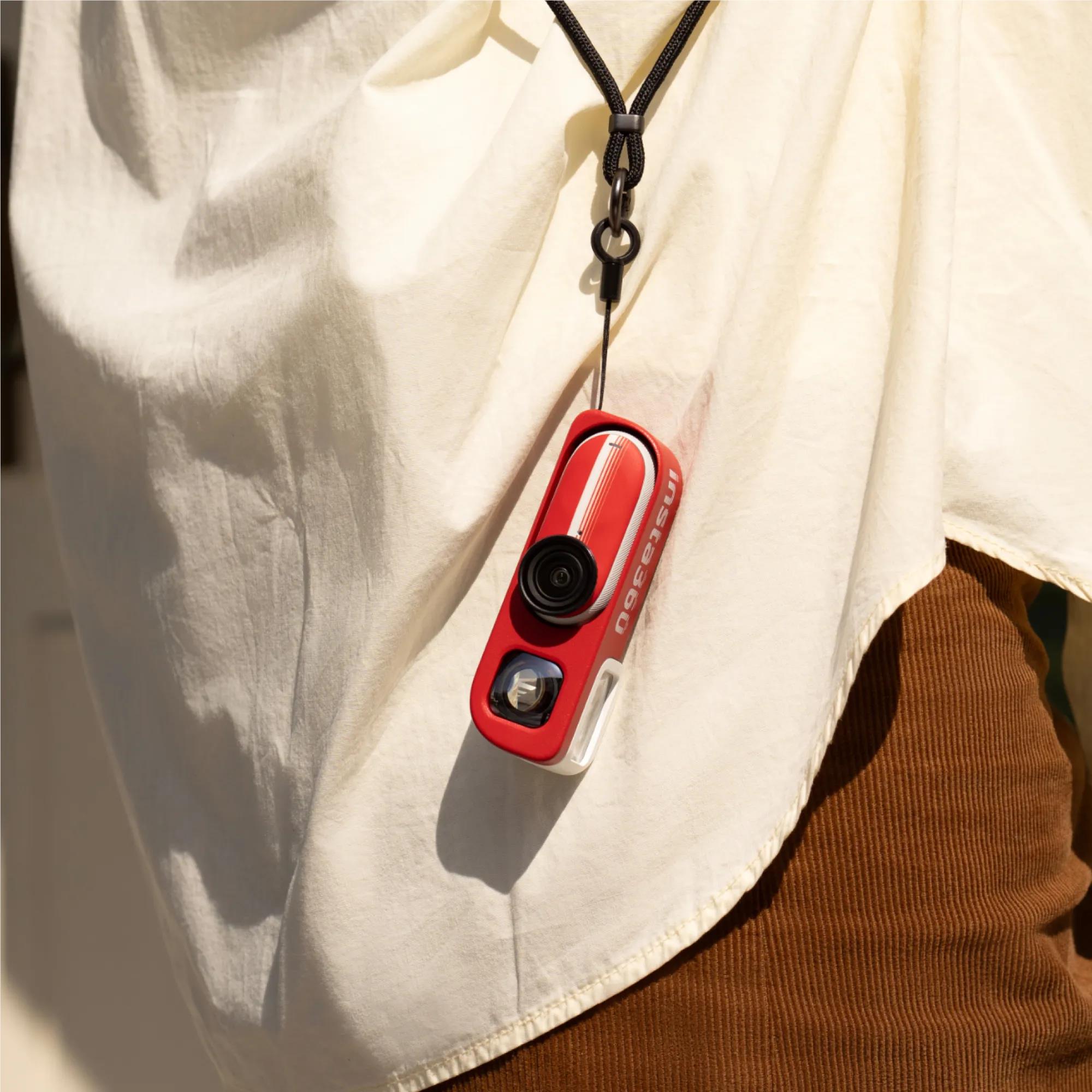 Red action camera on black lanyard clip attached to white fabric