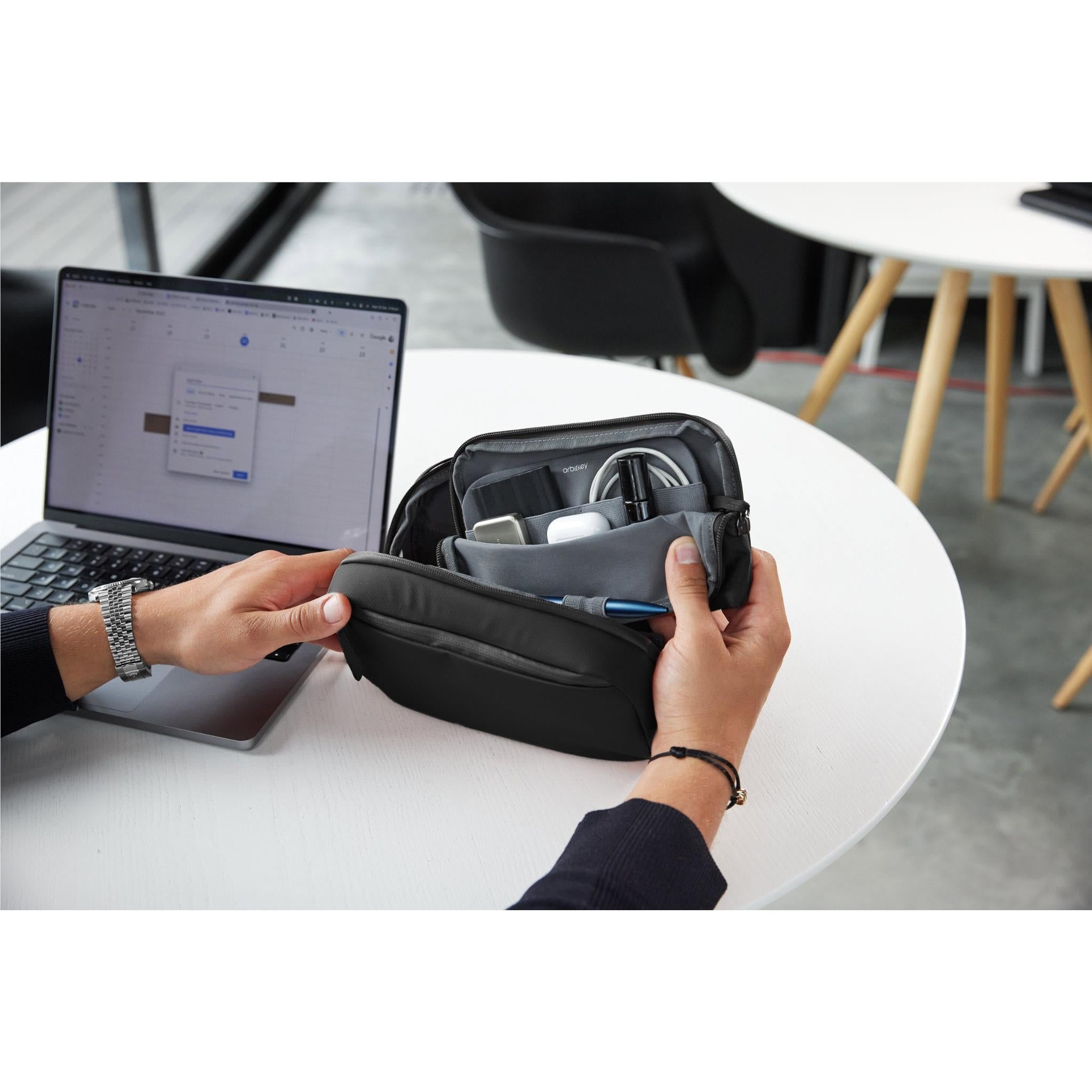 Black tech pouch organiser open on a desk with internal cable accessories