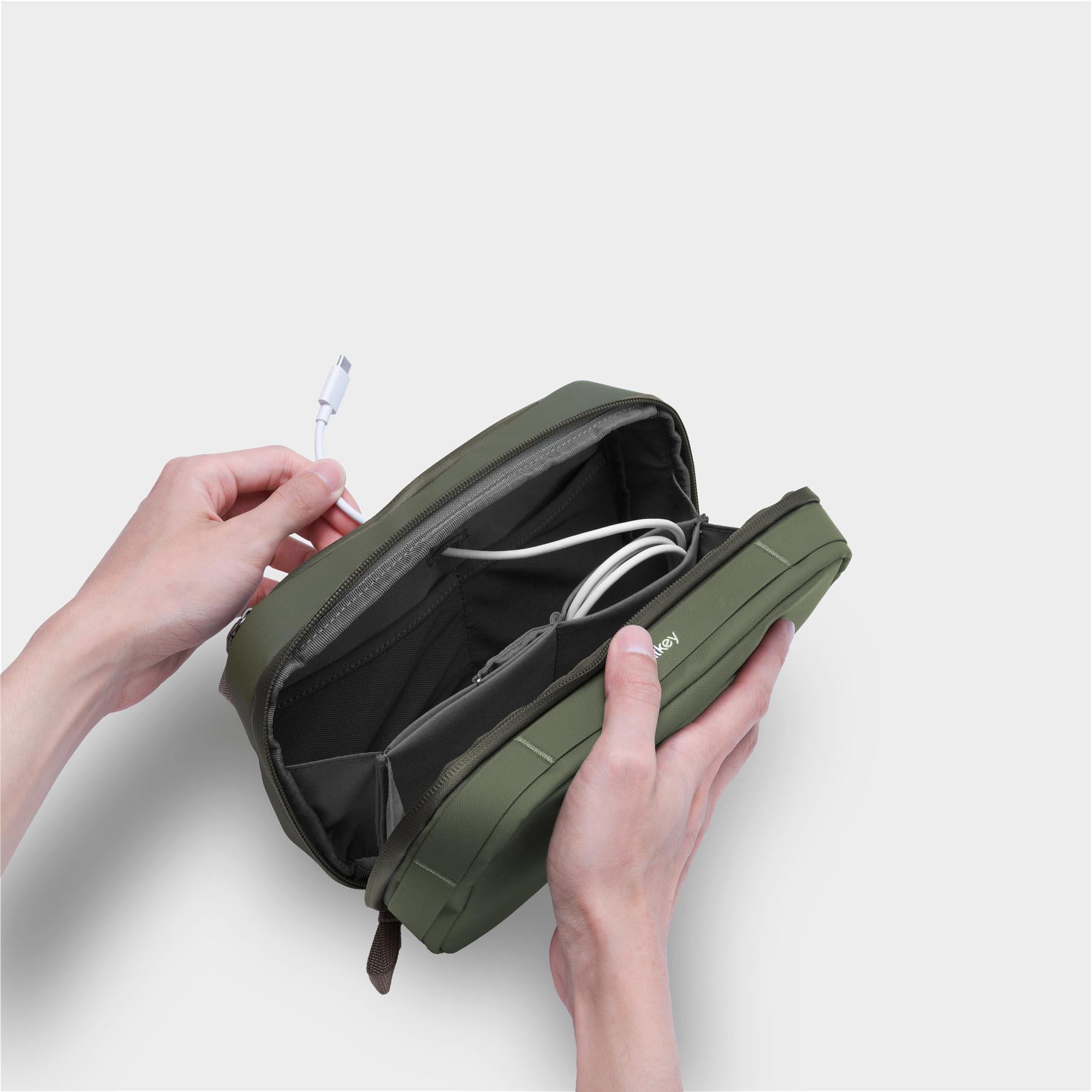 Olive green tech pouch opened with organized cable compartments and elastic holders