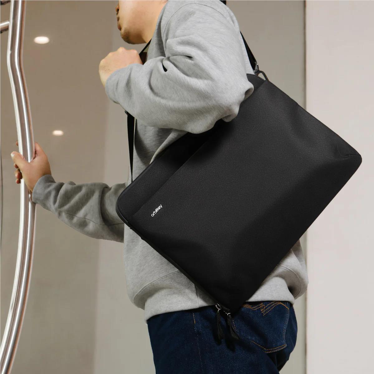 Black laptop sleeve with strap, carried in front of the body