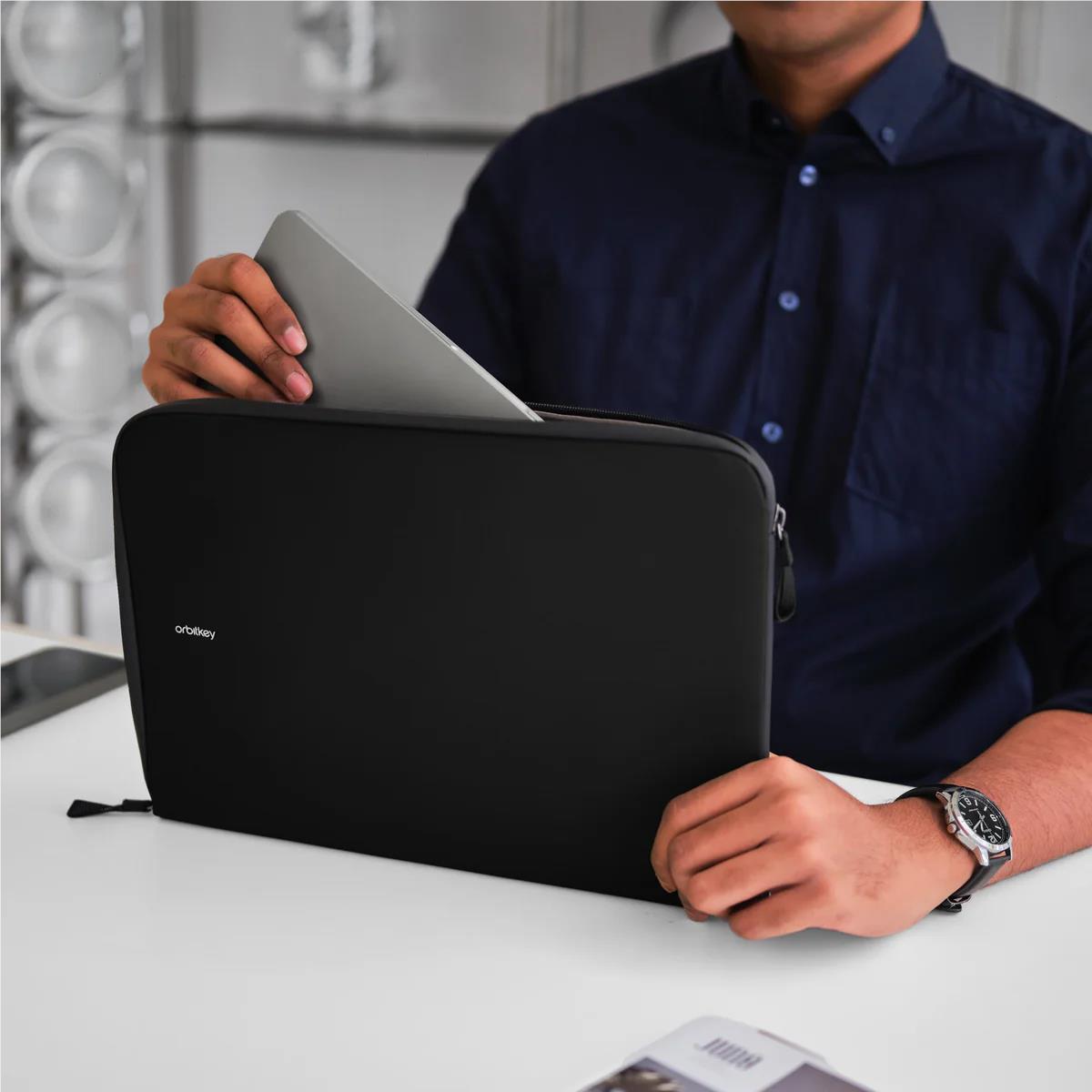 Black laptop sleeve with zip opening, held while inserting a laptop