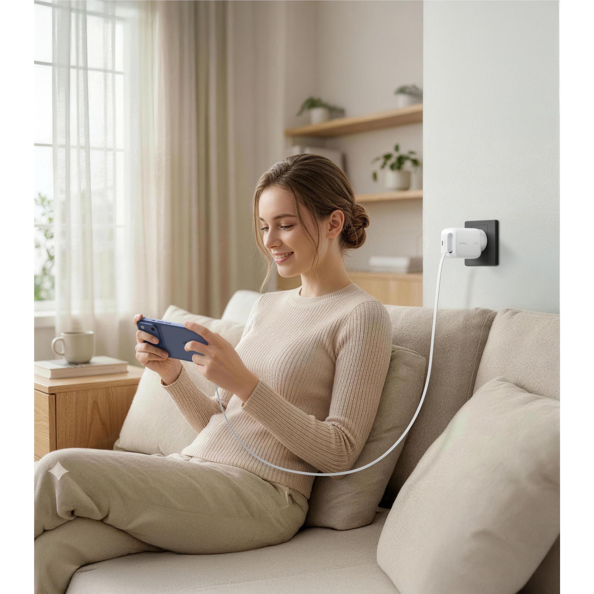 White wall charger on wall with USB-C cable charging a tablet on couch