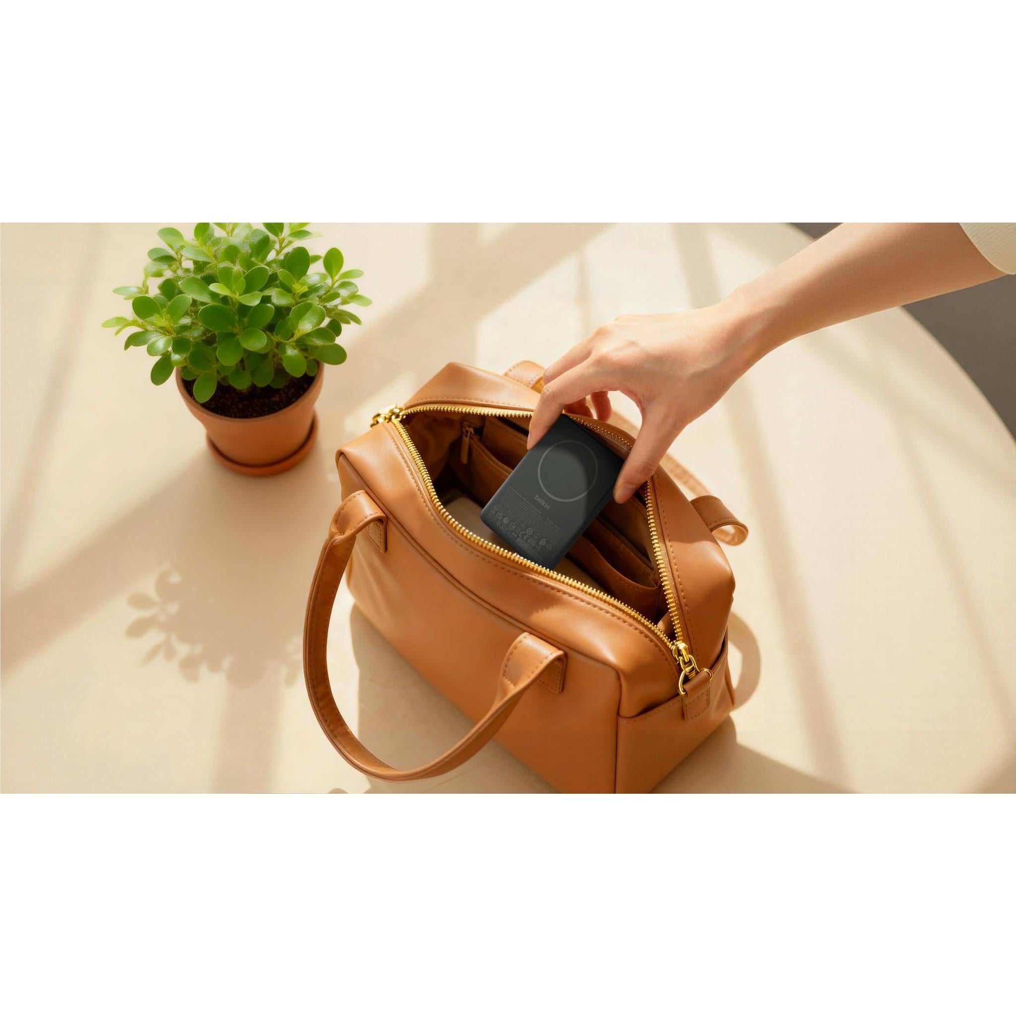 Black slim magnetic power bank being placed into a bag