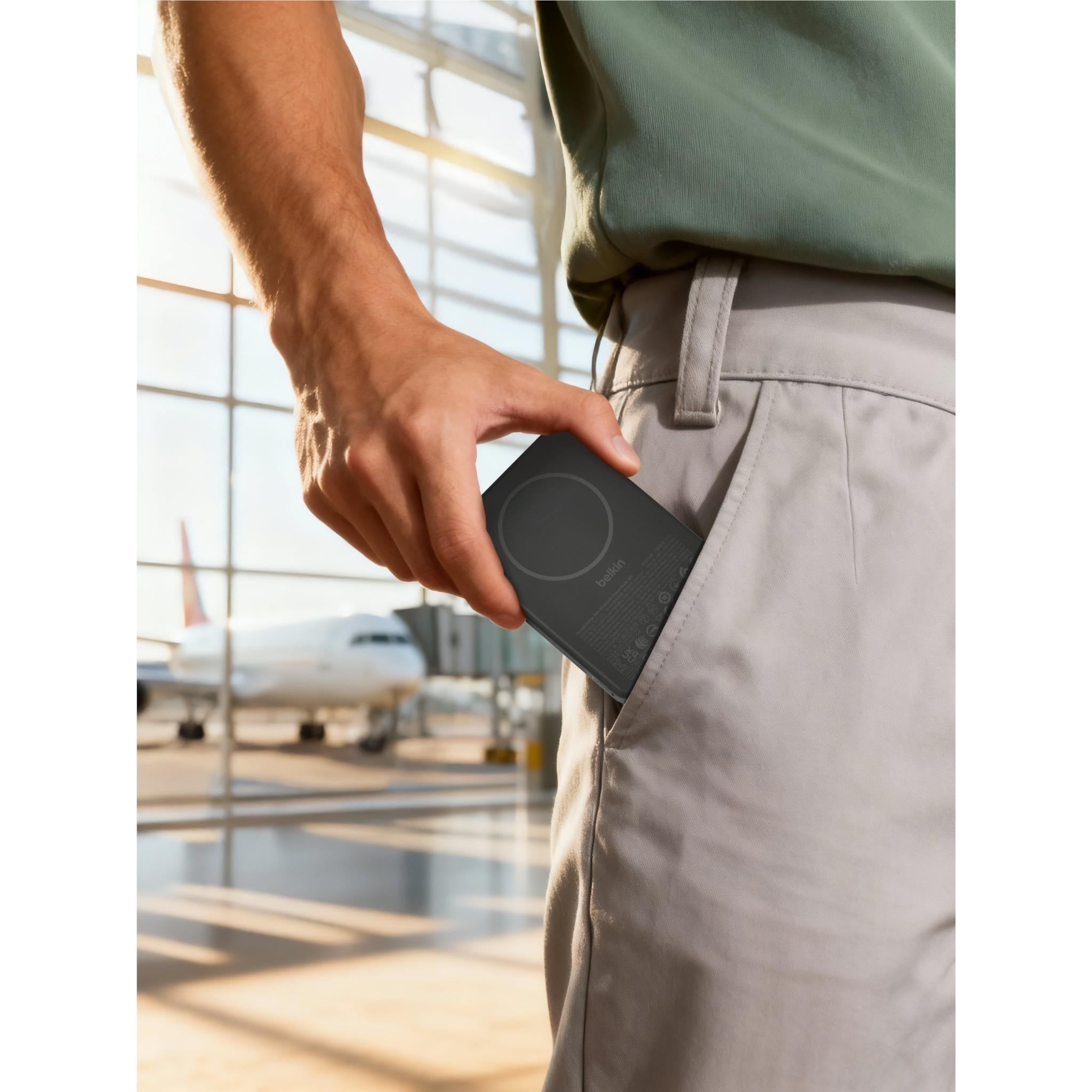 Black slim magnetic power bank in hand near a pocket