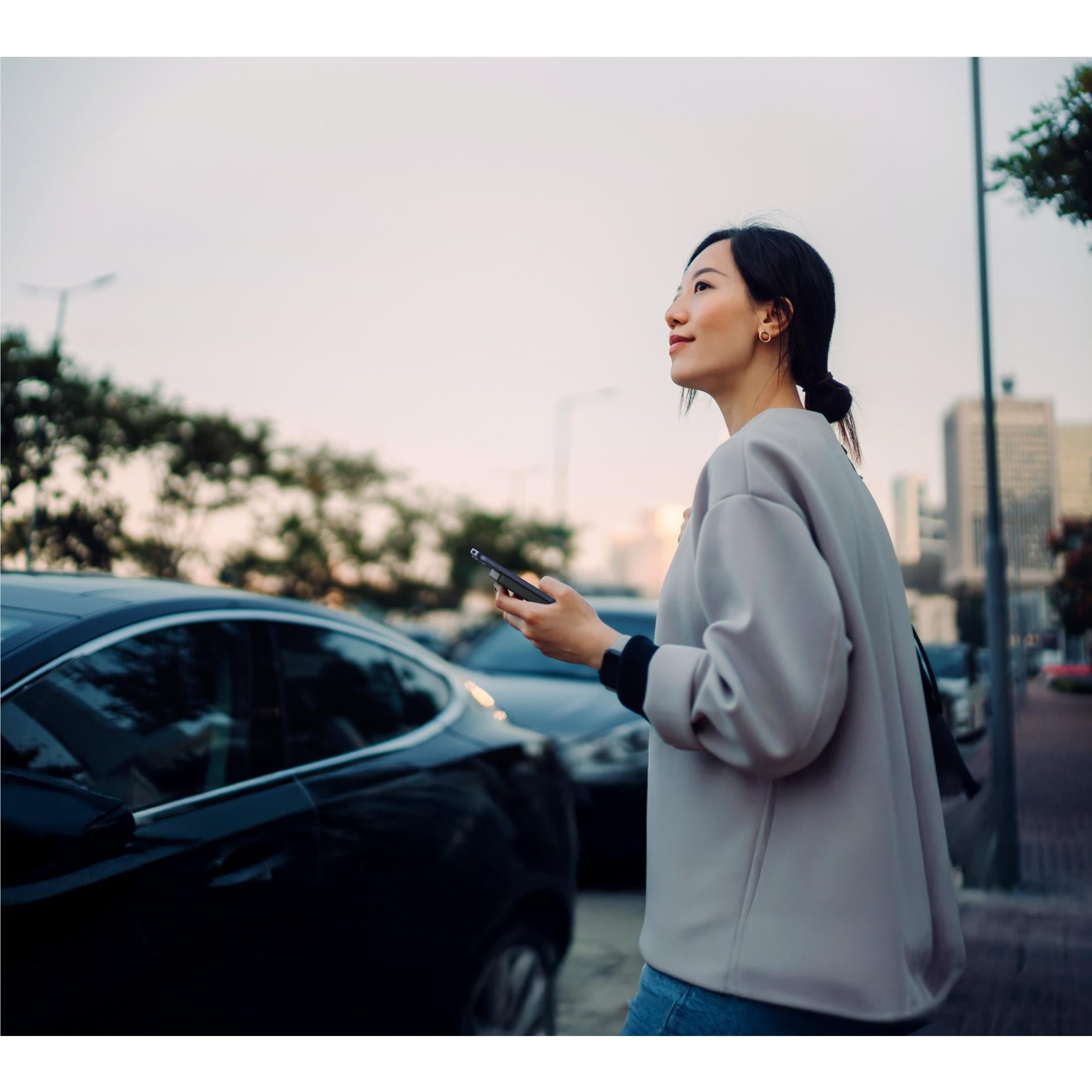 Woman holding a slim black magnetic power bank outdoors