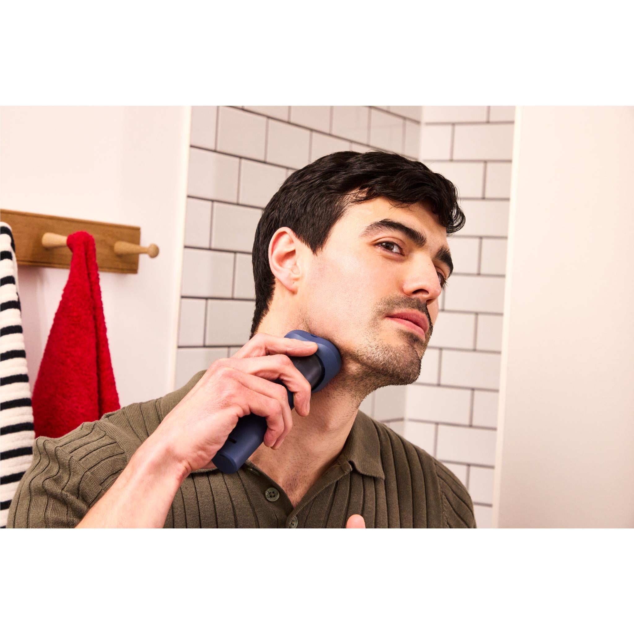 Man using blue Remington rotary shaver on face; three circular heads visible